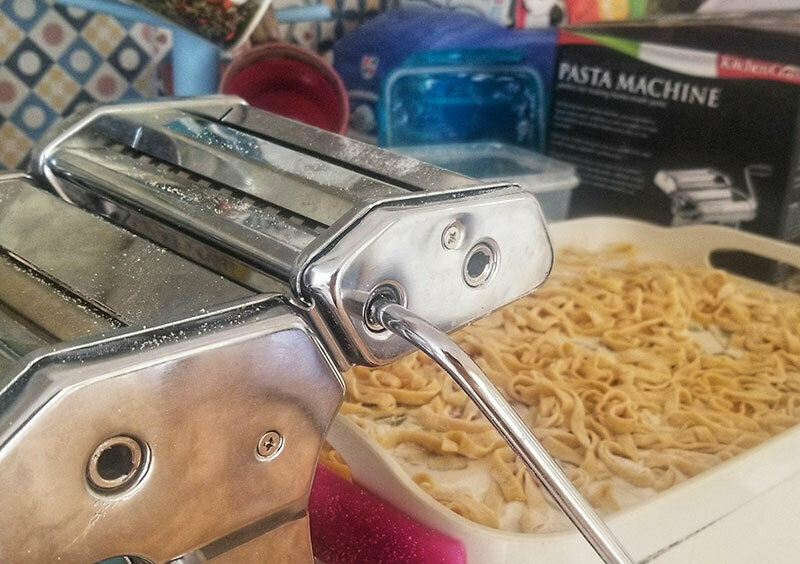 A pasta machine, with a tray of fresh tagliatelle that's just been put through it.