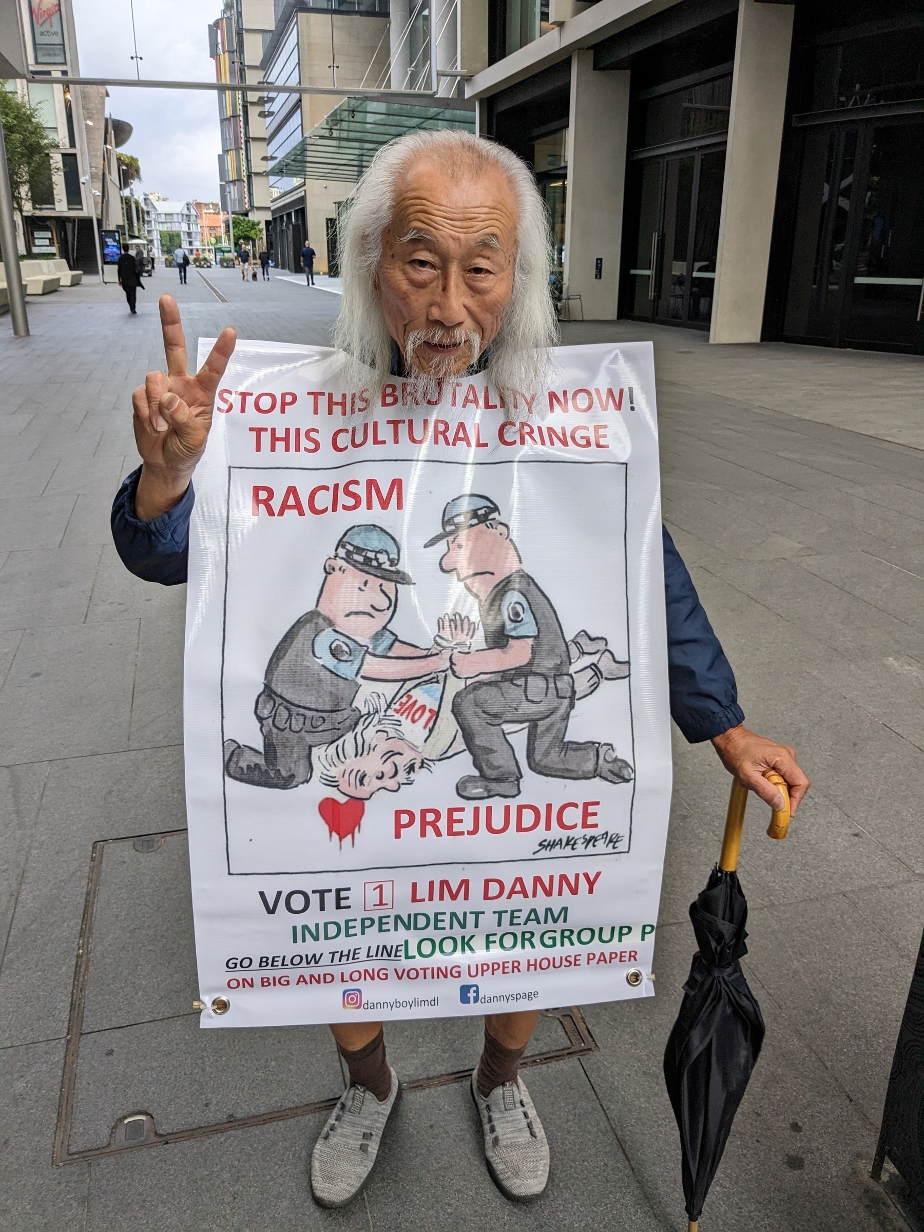 An old man wearing a sandwich board protesting against police violence and saying to vote for him in the state election.