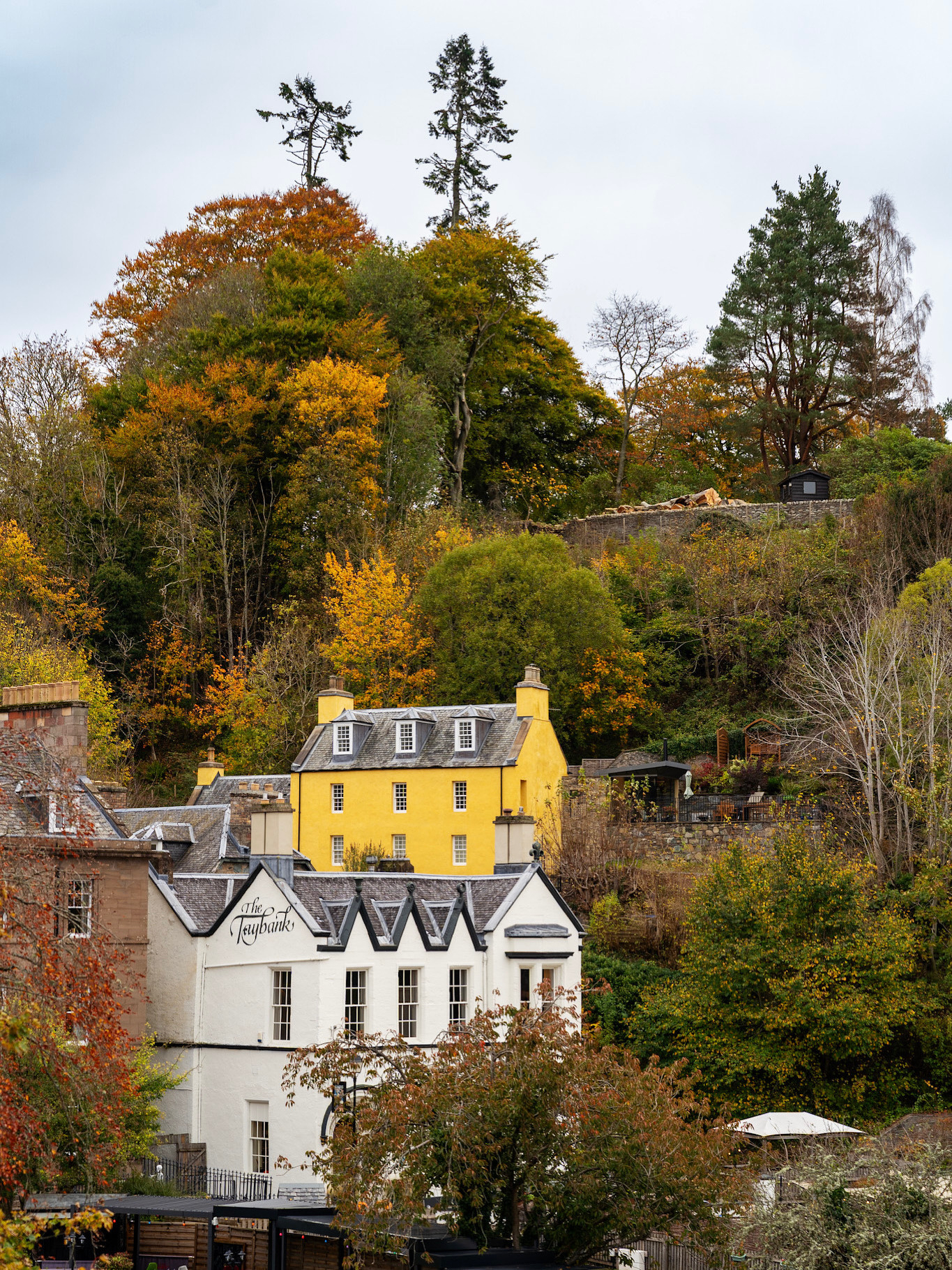 A yellow house in Dunkeld against autumn leaves