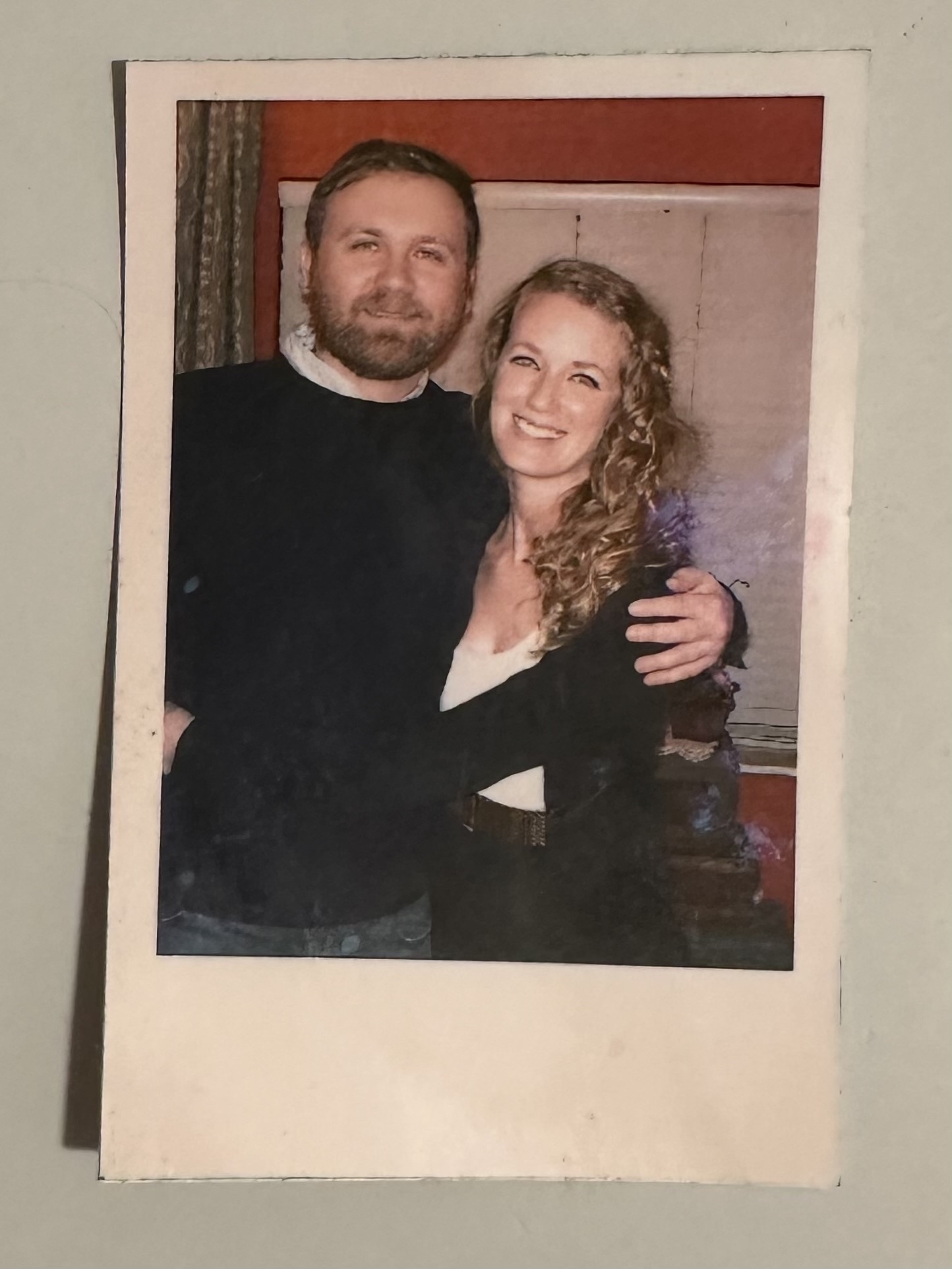 A photo of two people side hugging in a house. 