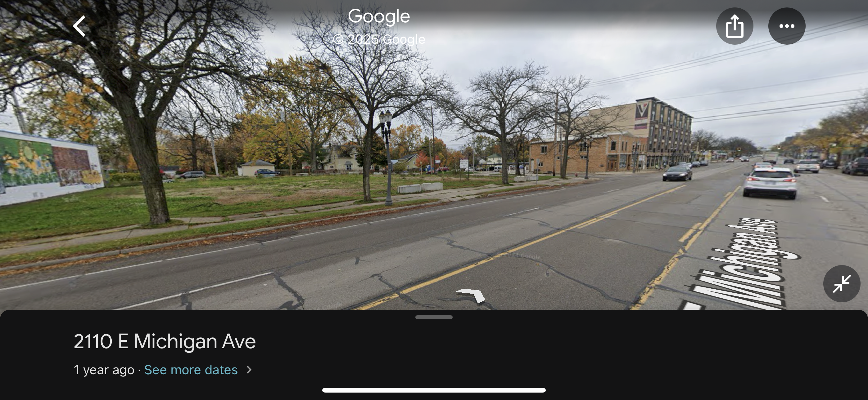 A street view shows a multi-lane road lined with bare trees, grassy areas, and a brick building.