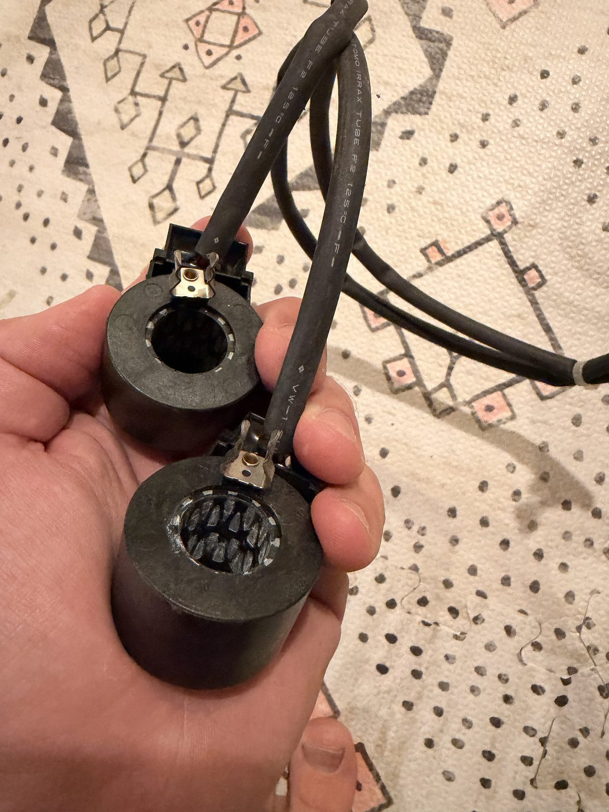 Two black stepper motor coils on a single wiring harness, held in a hand