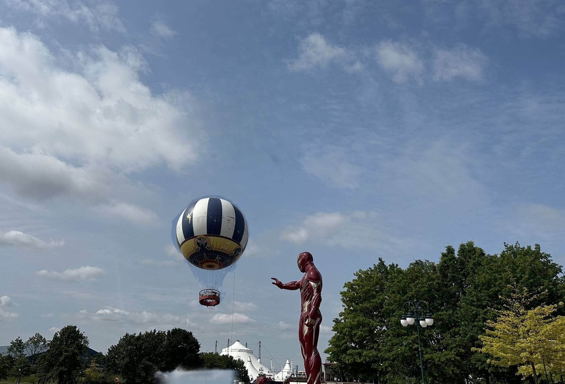 Large Iron Man statue with hot air balloon in background.