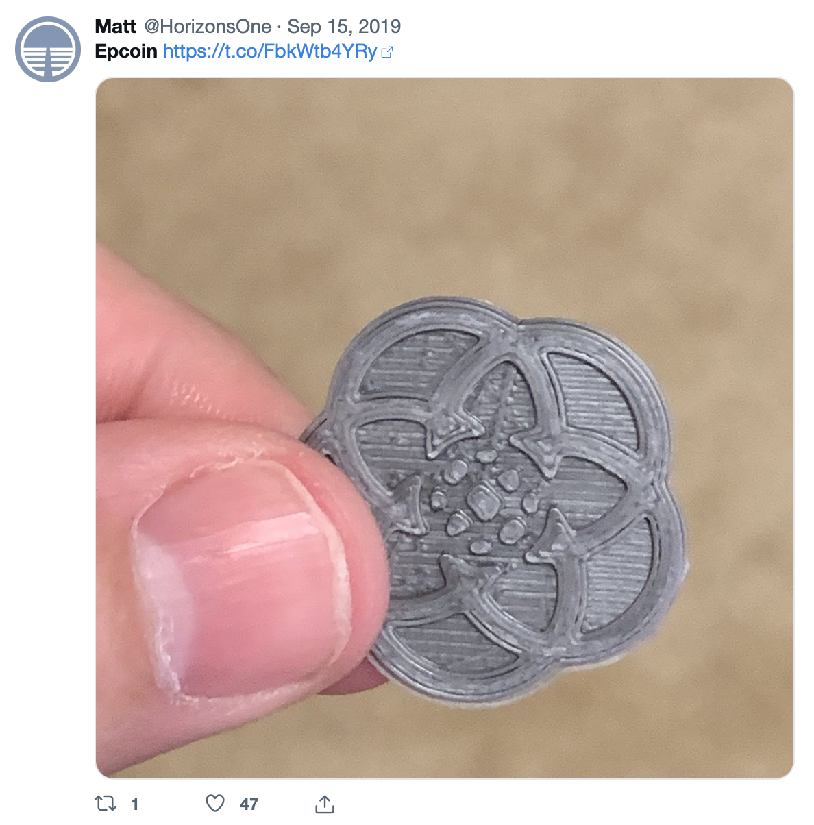 A silver coin-sized epcot logo.