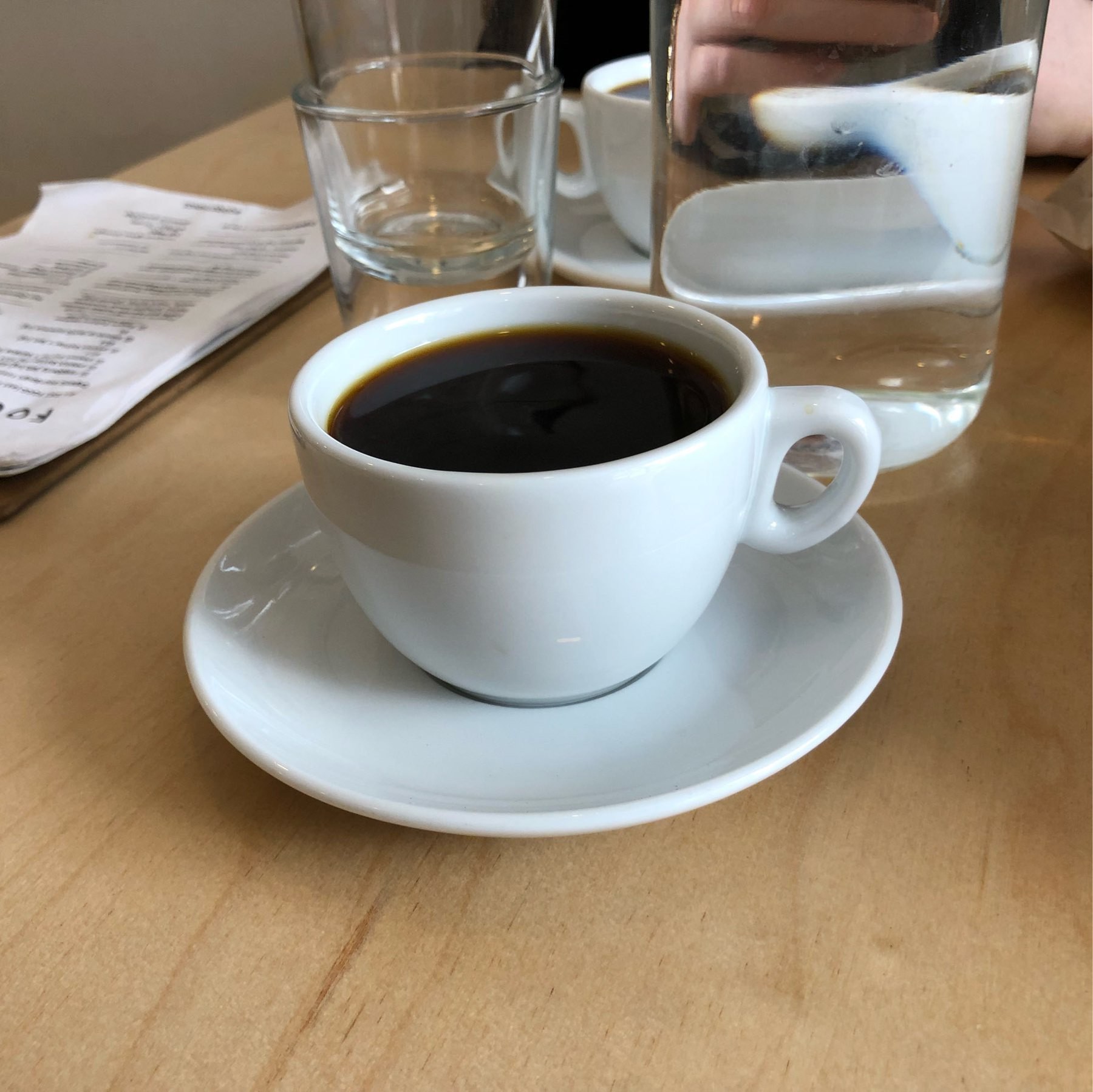 Black coffee in a white cup with a white saucer.