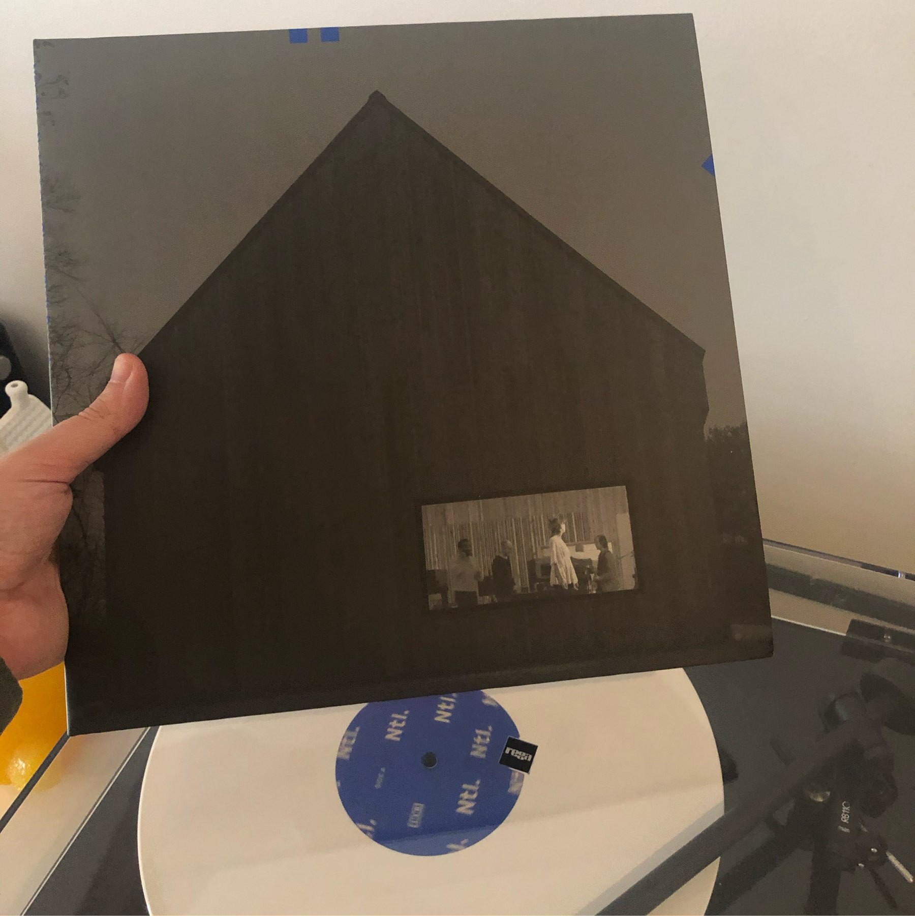 Record playing, showing cover which is a dark house with the view of the living room.