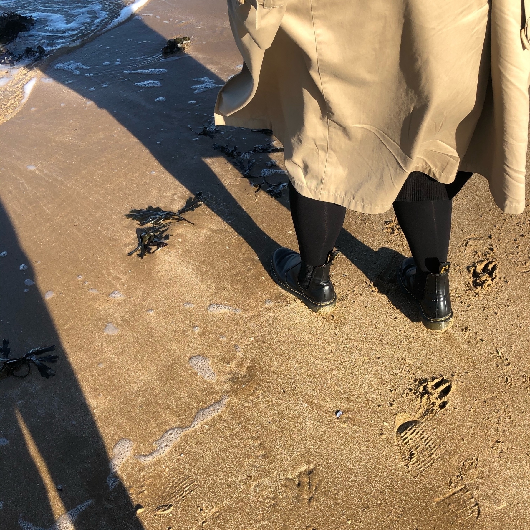 Sand with annas black boots and brown jacket as we walk along the sea
