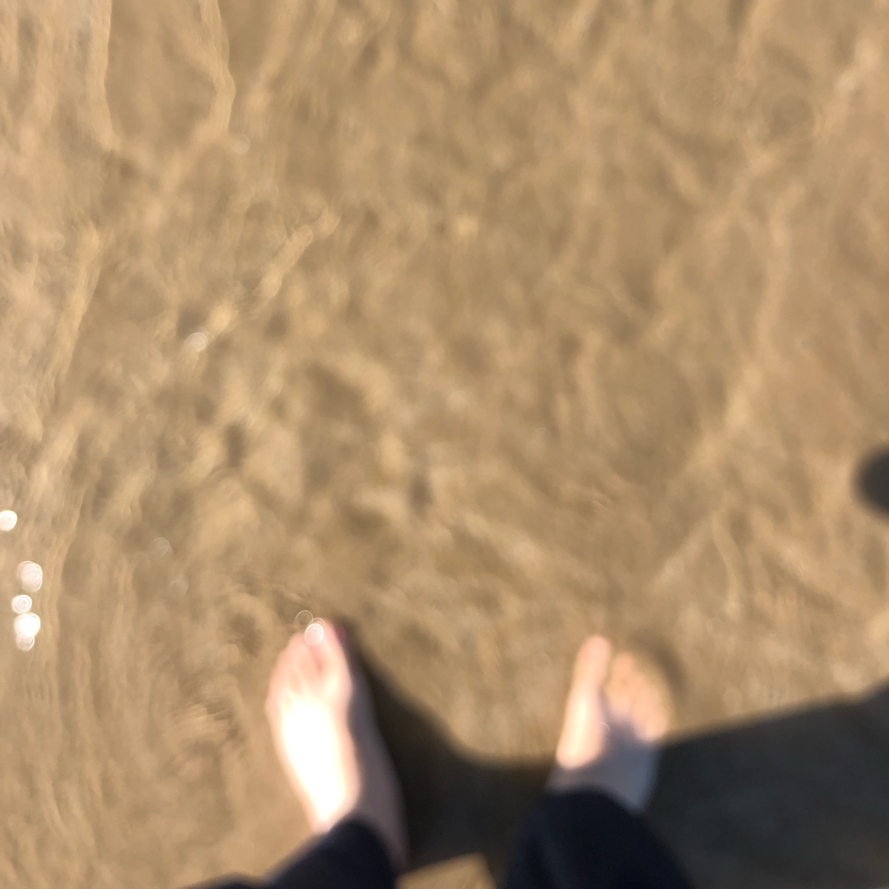 feet in the sand with water over them