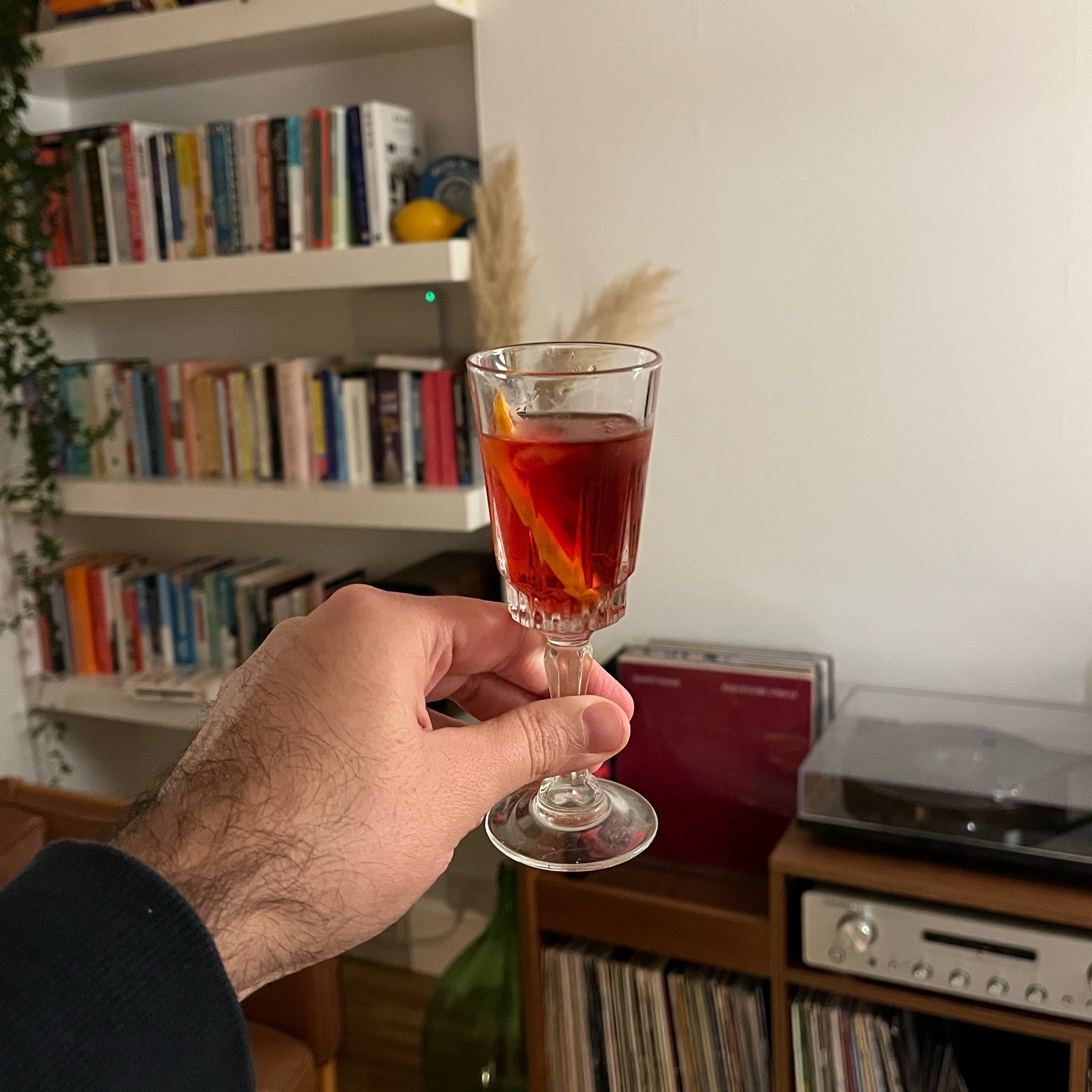 Negroni on a small glass hold up to a white wall