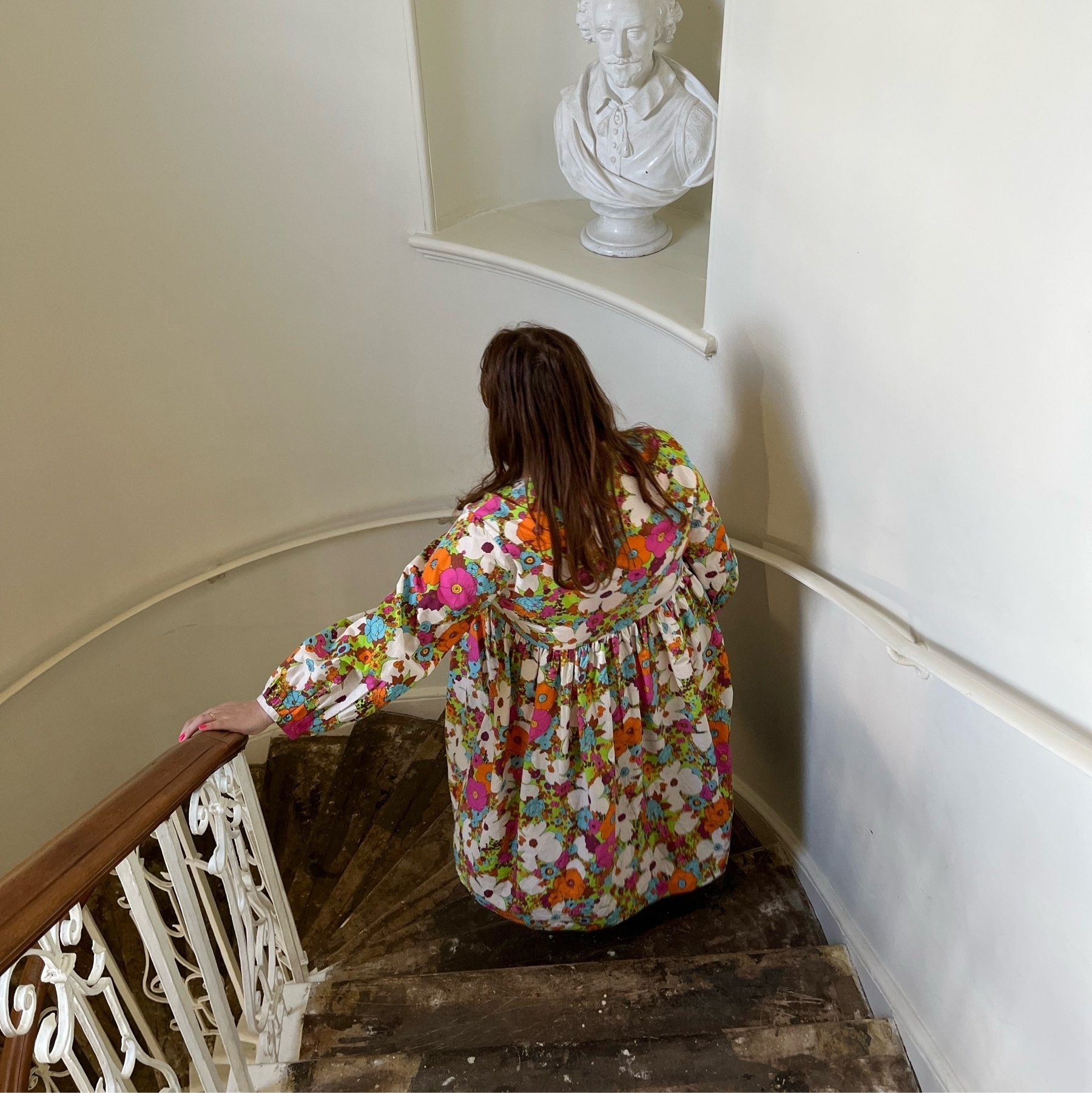 Anna walking down the stairs wearing a flowery dress