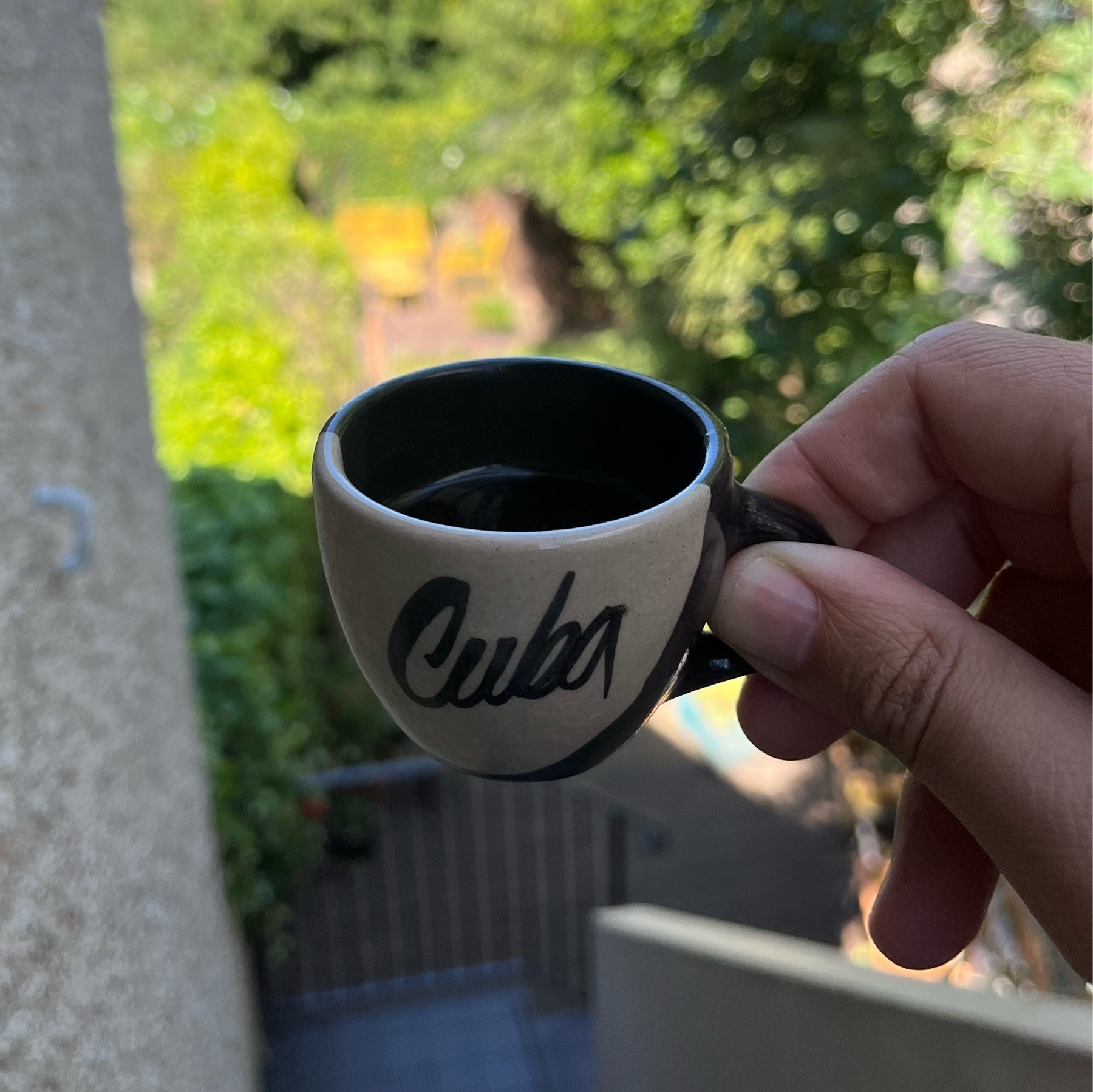Small coffee cup that says cuba with garden at the background