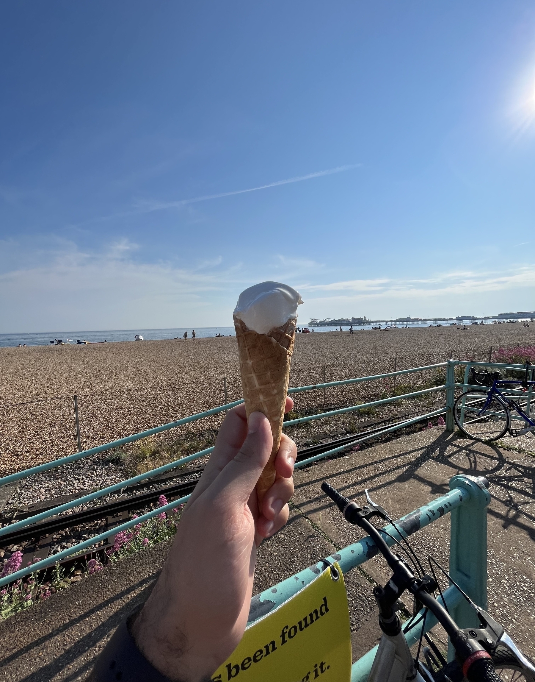 Holding a cone ice cream against the beach with clear blue skies and the background sea