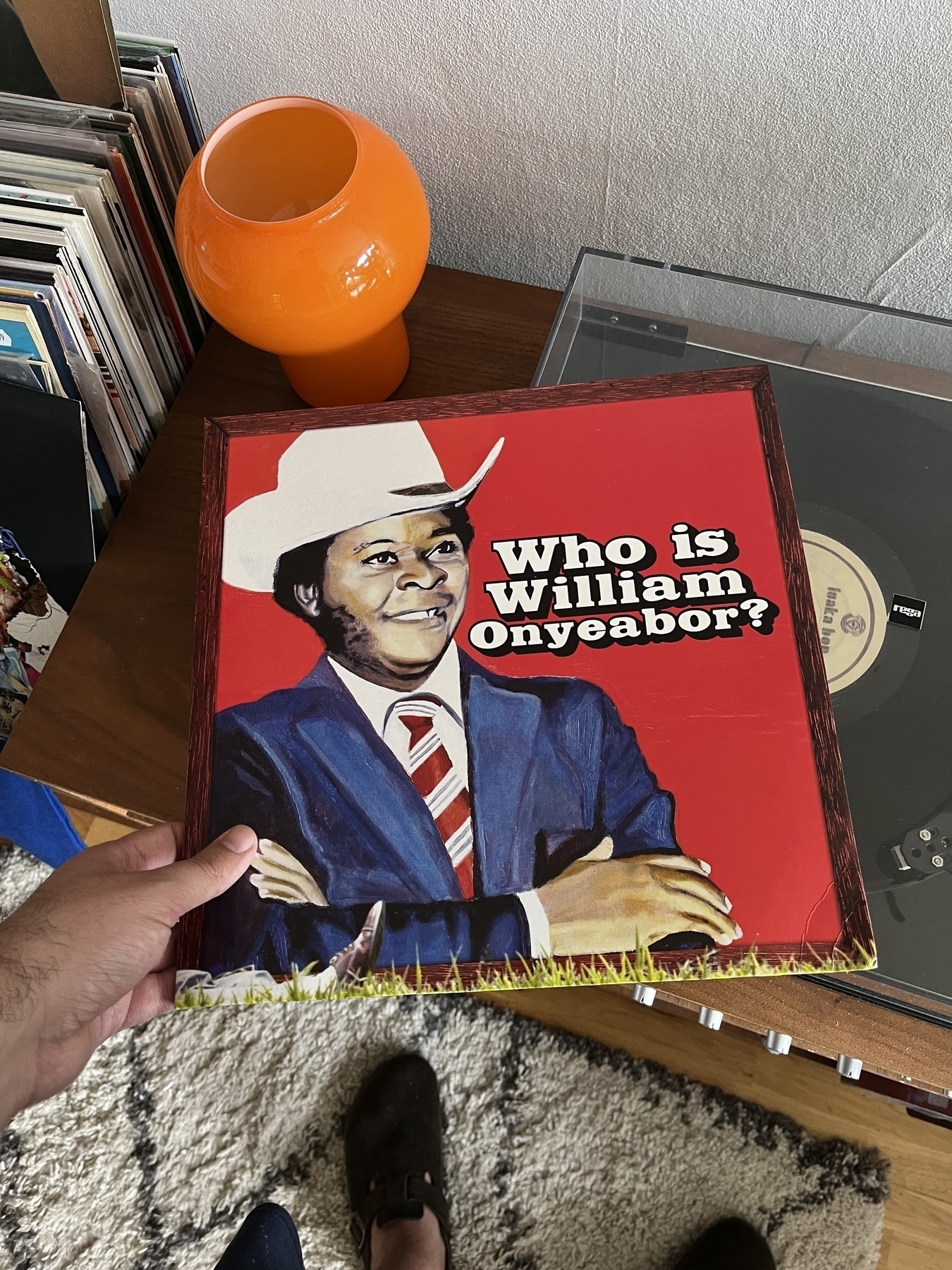 Record cover siting on top of a record player with a record moving, cover shows a Nigerian man wearing a white top hat.