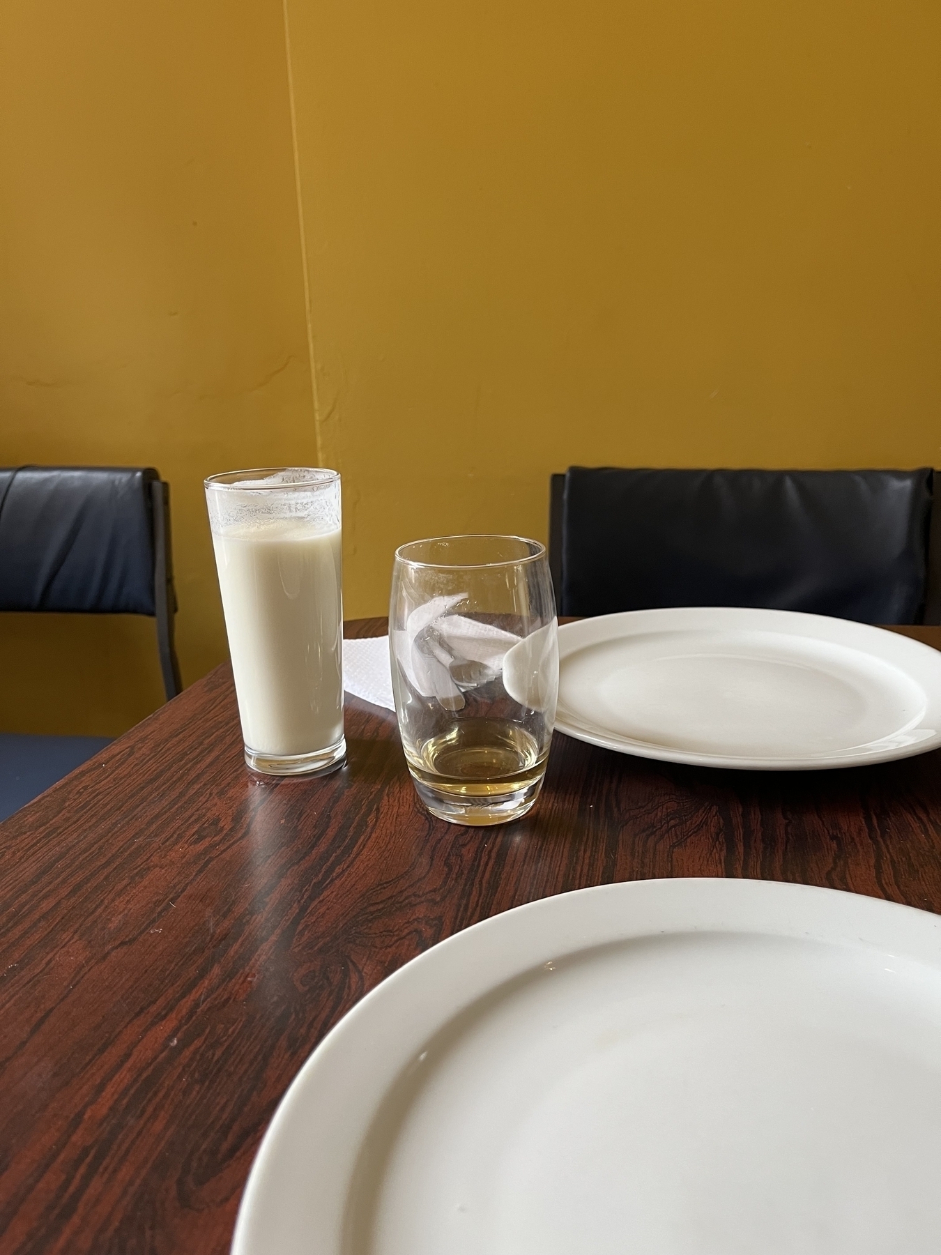 Two drinks on a table, Lasi white yogurt drink a nearly empty beer and a white table empty.