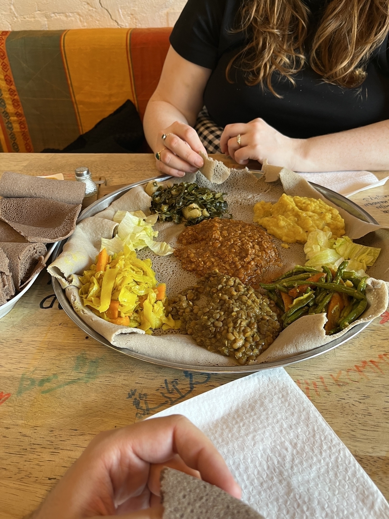 Ethiopian round dish with different types of lentils, beans and cabbages in a round metal dish.