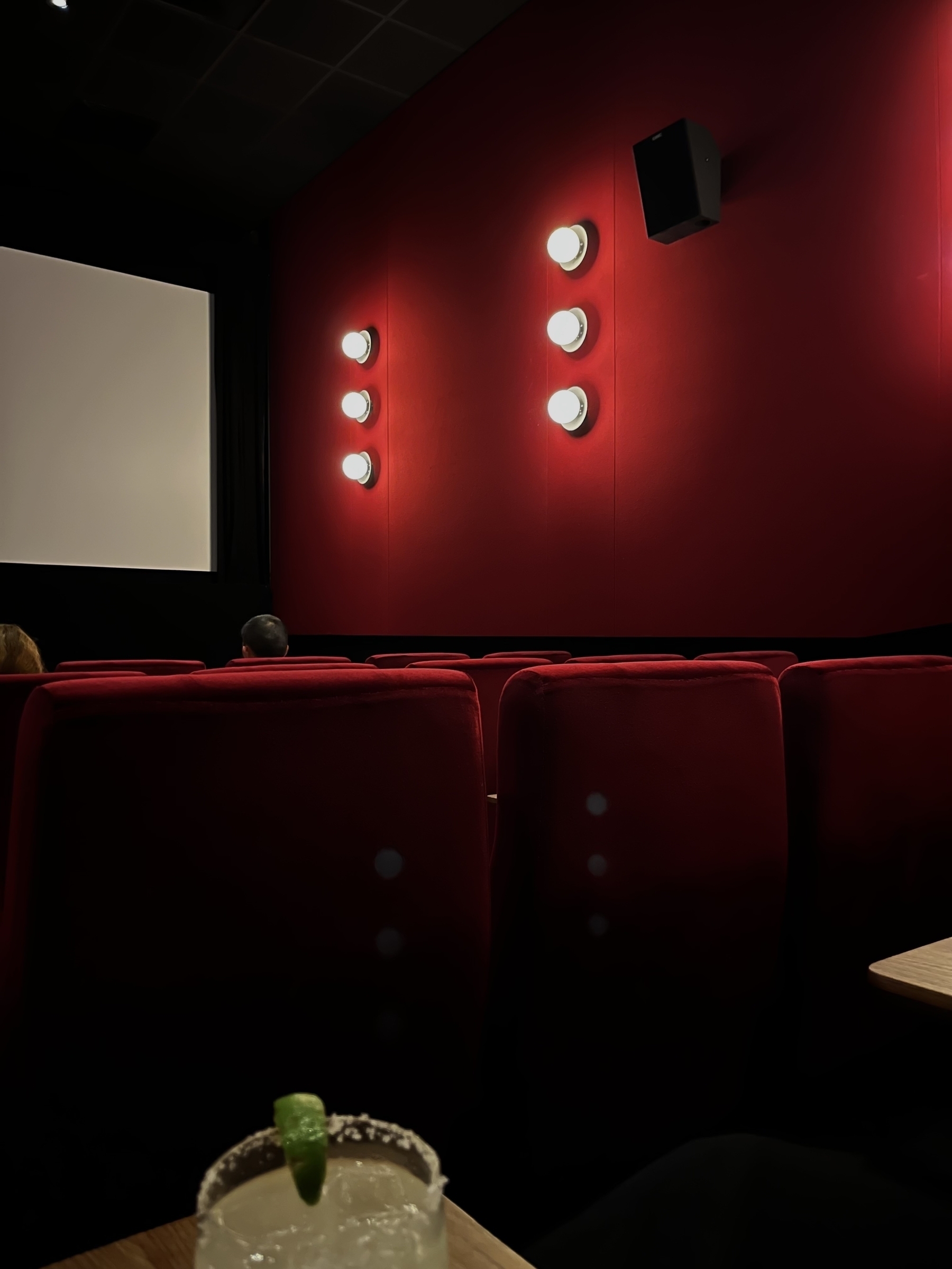 Cinema room with bright red walls and bright lights, can be seen  from a red velvet seat