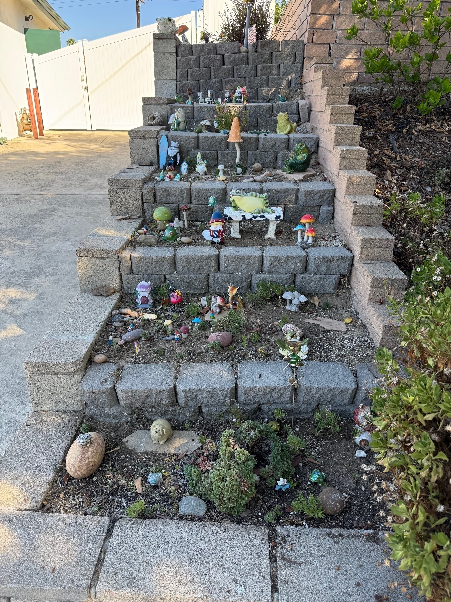 Terraced hill with cinder blocks supporting the terracing and garden gnomes and mushrooms and shit on the steps.