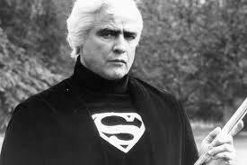 Marlon Brando looking dapper with white hair and wearing a turtleneck with a Superman logo on it