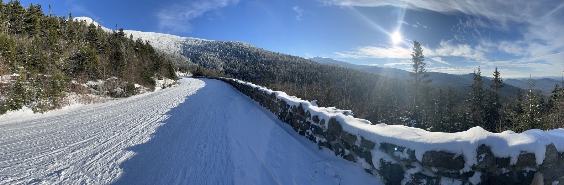 Panorama of a snowy mountain road with a castle at the top.