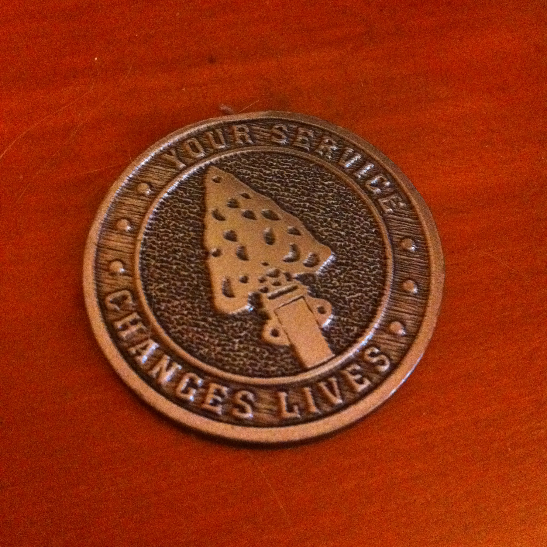 A coin depicting an arrowhead with the inscription, “Your service changes lives.”
