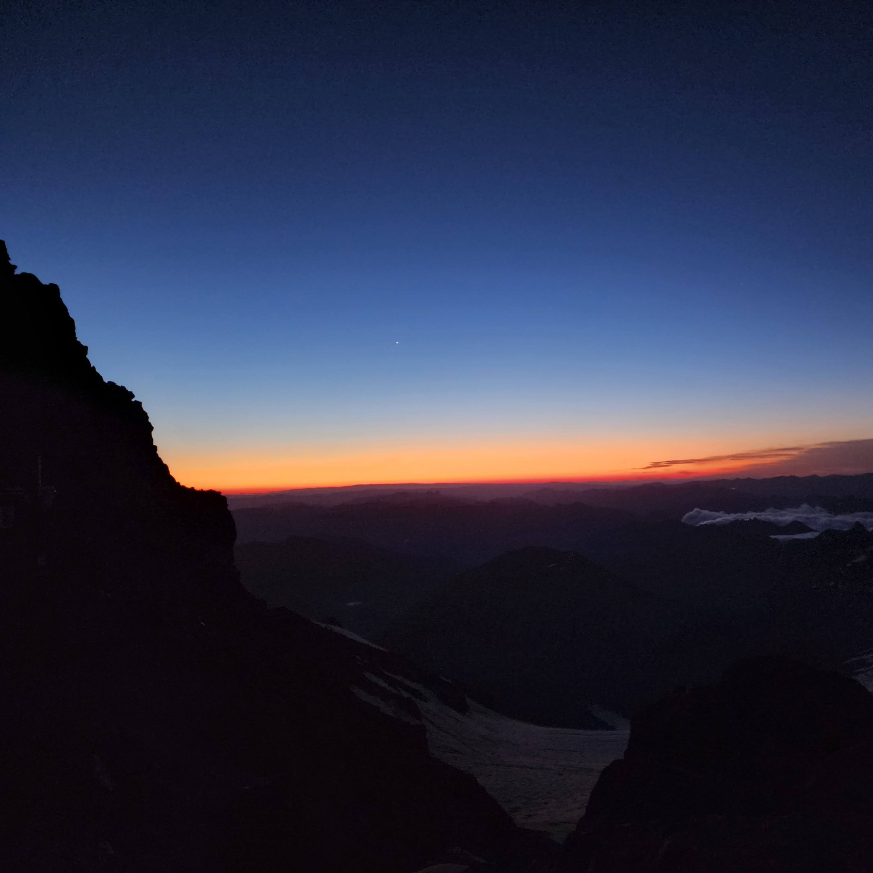 A dark sunrise from the view of a mountainside.