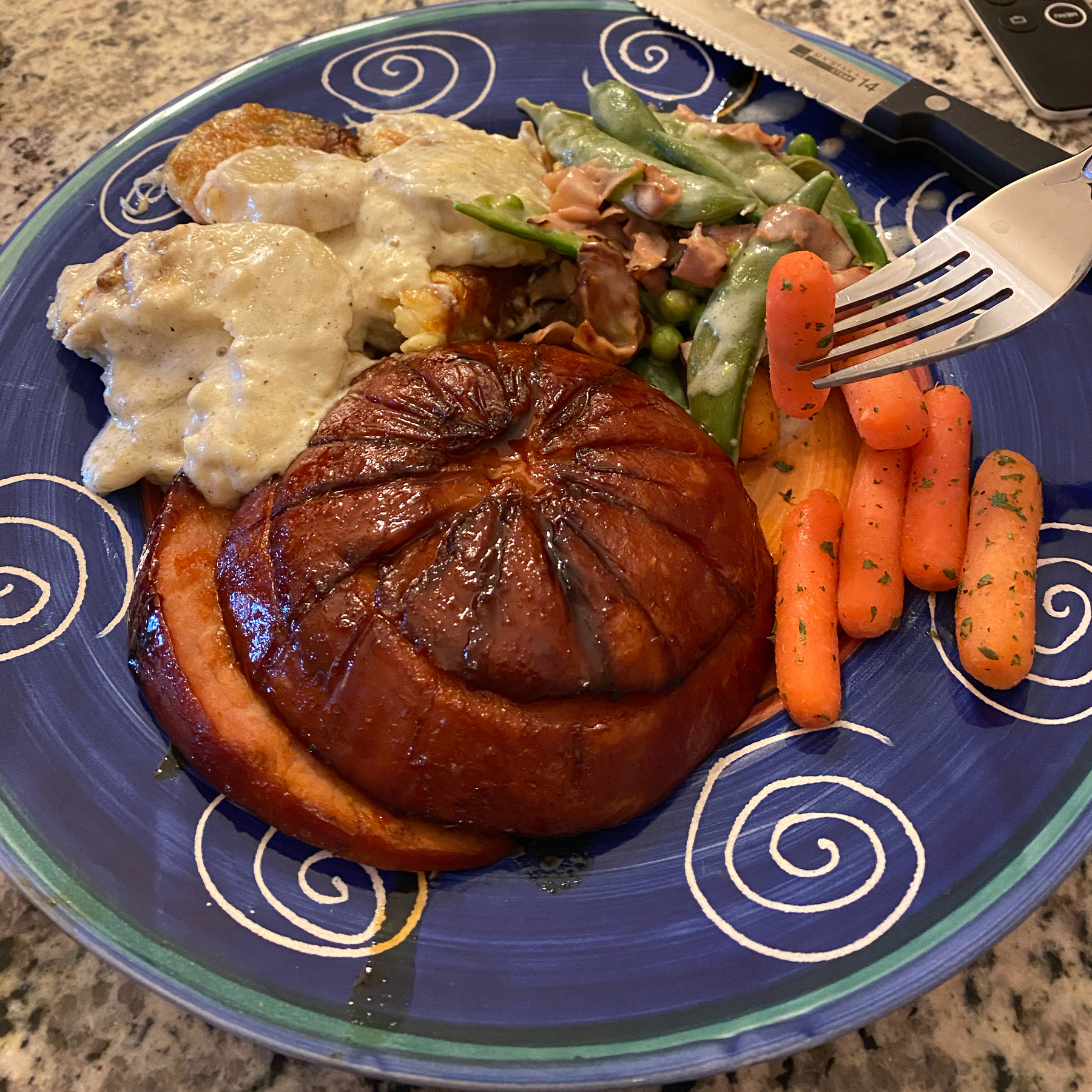 A plate of food including mashed potatoes and glazed spiral ham.