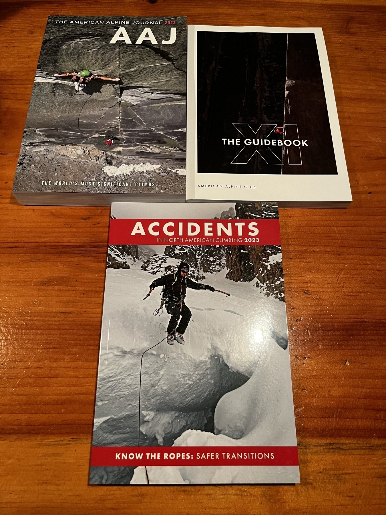 Three books on the counter, including the American Alpine Journal 2023, the guidebook number 11, and accidents in North America climbing 2023 all from the American Alpine club