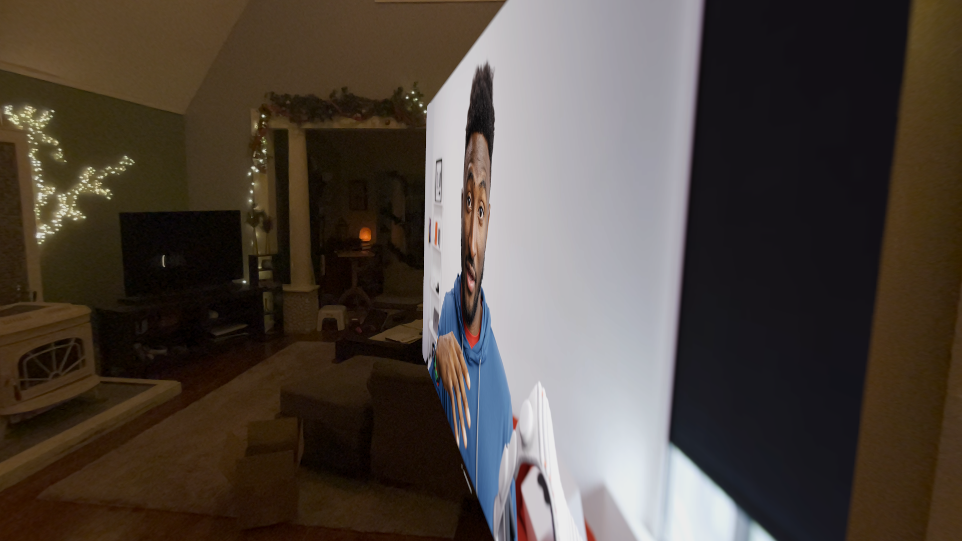A large, three-dimensional head-and-shoulder depiction of a man emerges from a flat surface, dominating a dimly lit living room adorned with festive lights.