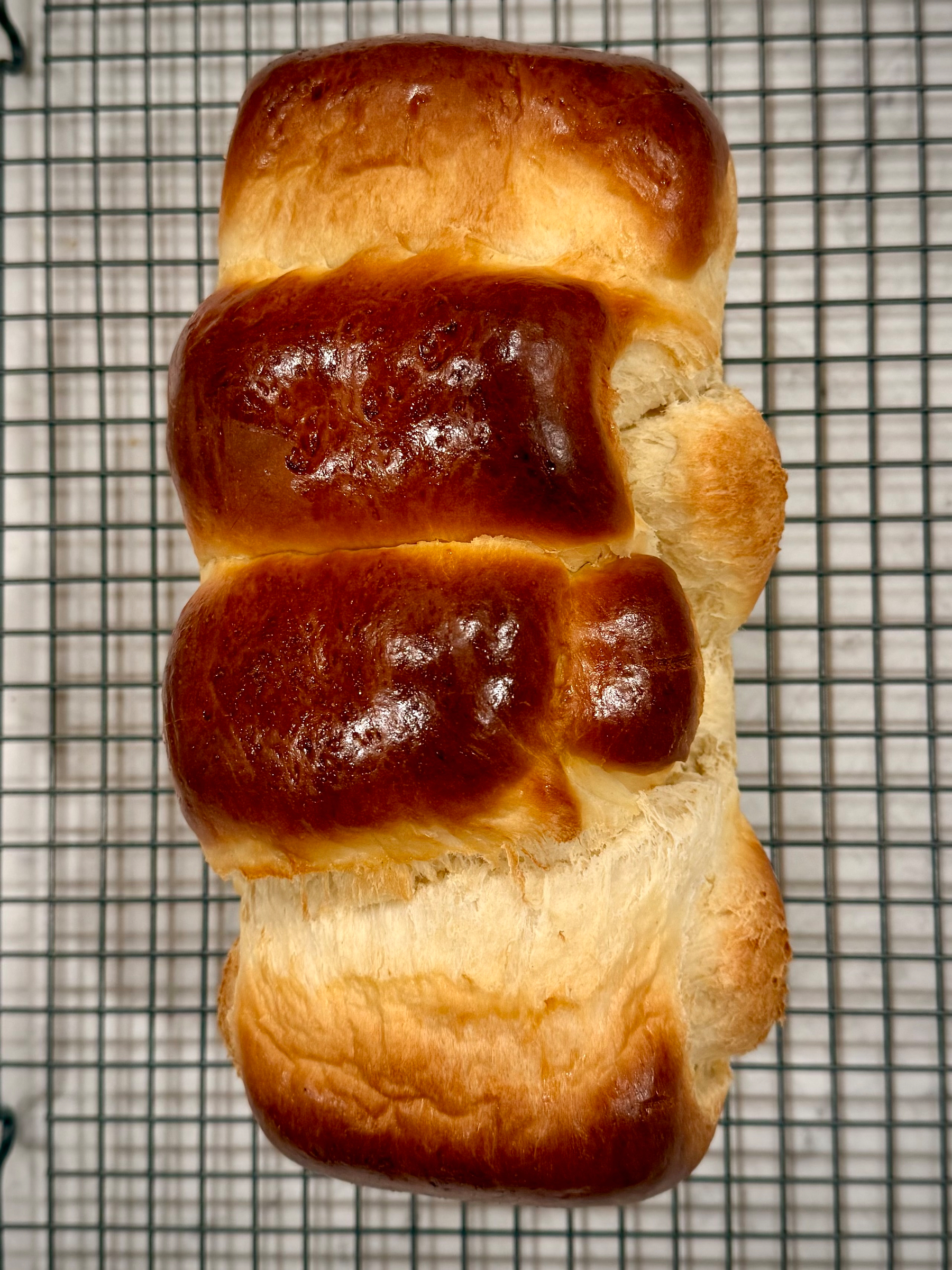 A golden-brown loaf of bread cooling on a wire rack.