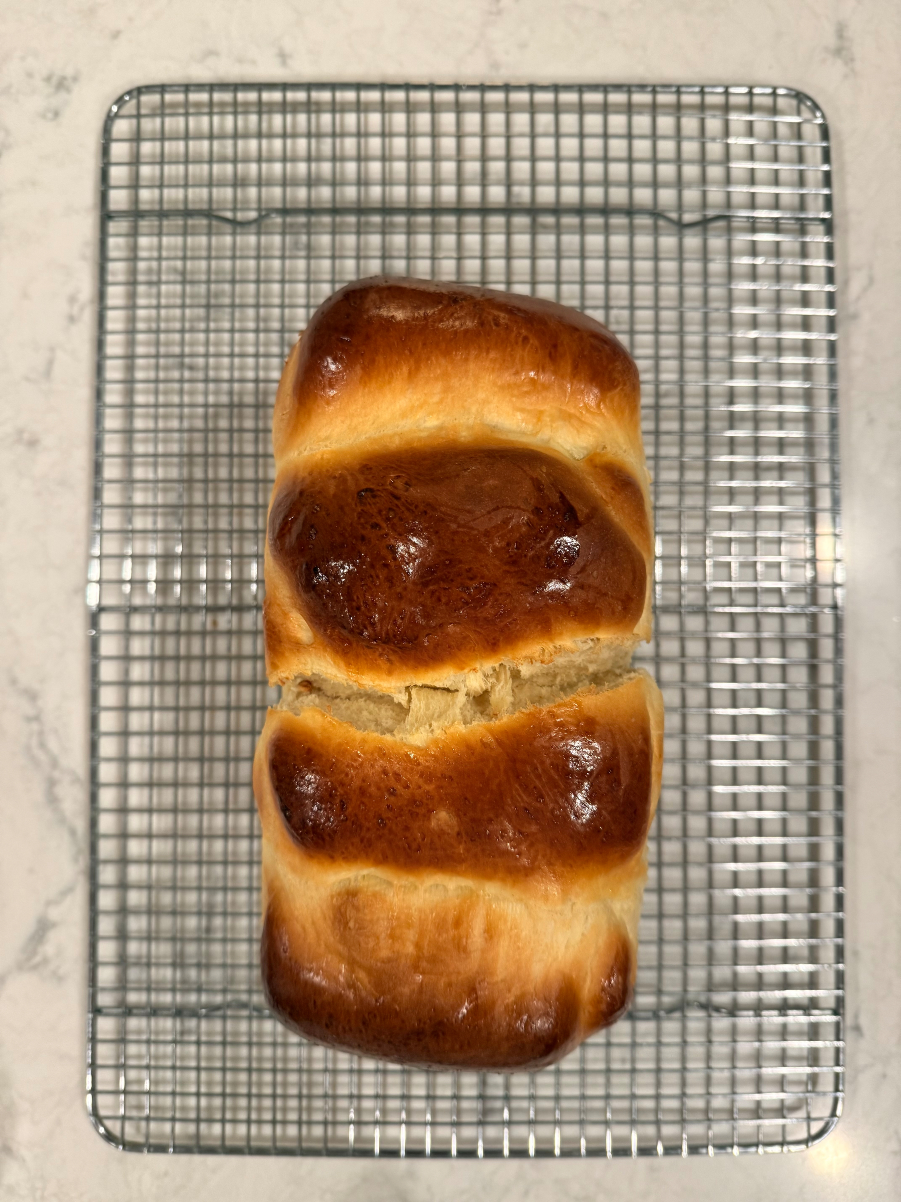 A freshly baked loaf of bread is cooling on a metal rack.