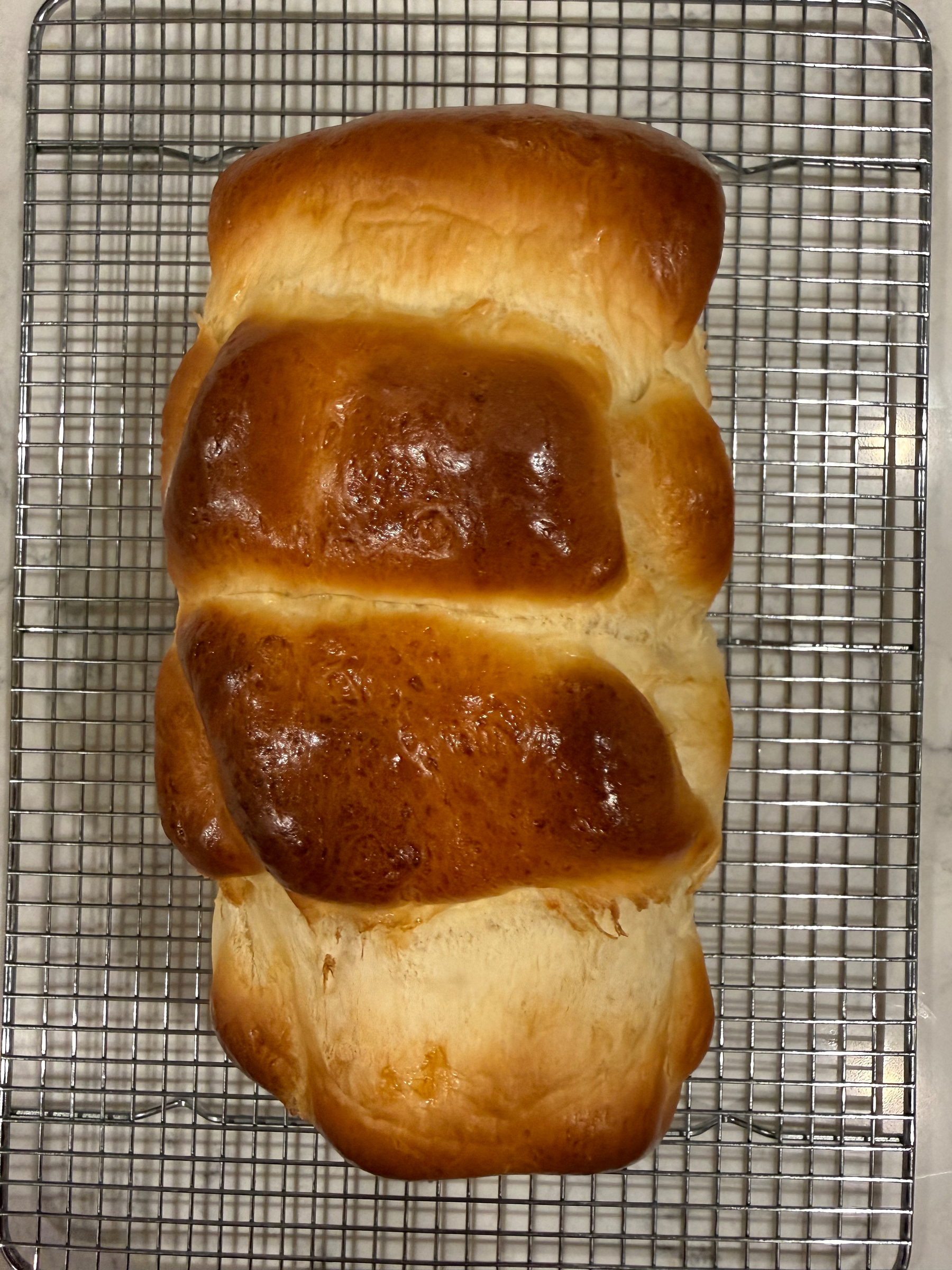 A freshly baked loaf of bread is resting on a cooling rack.