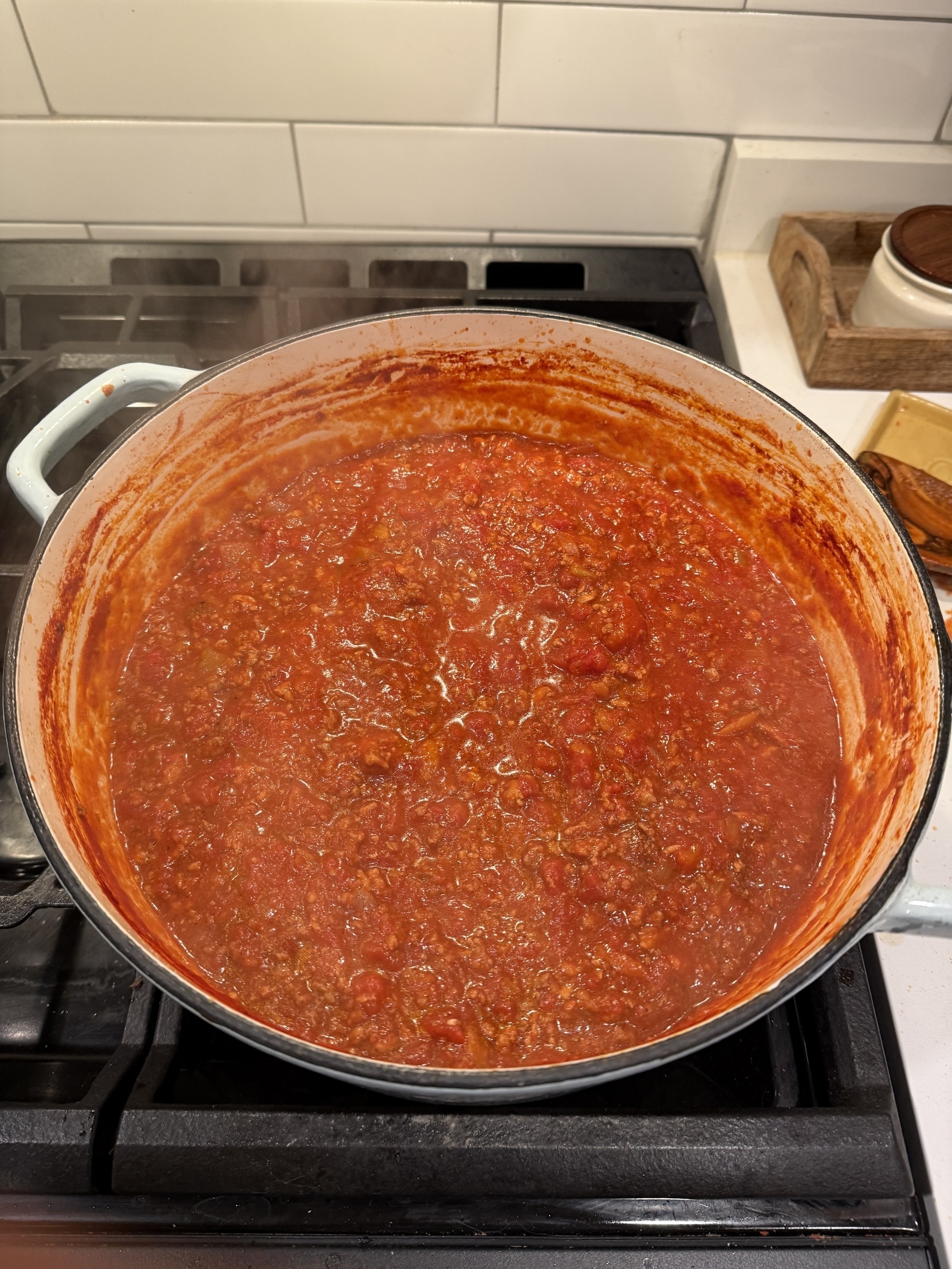A pot filled with rich, red tomato sauce simmers on a stovetop.