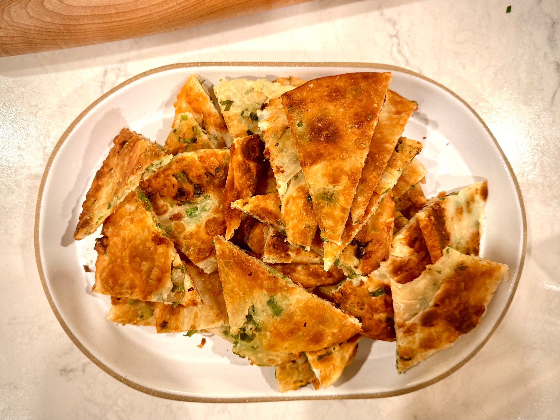 A plate filled with sliced pieces of golden-brown scallion pancakes.