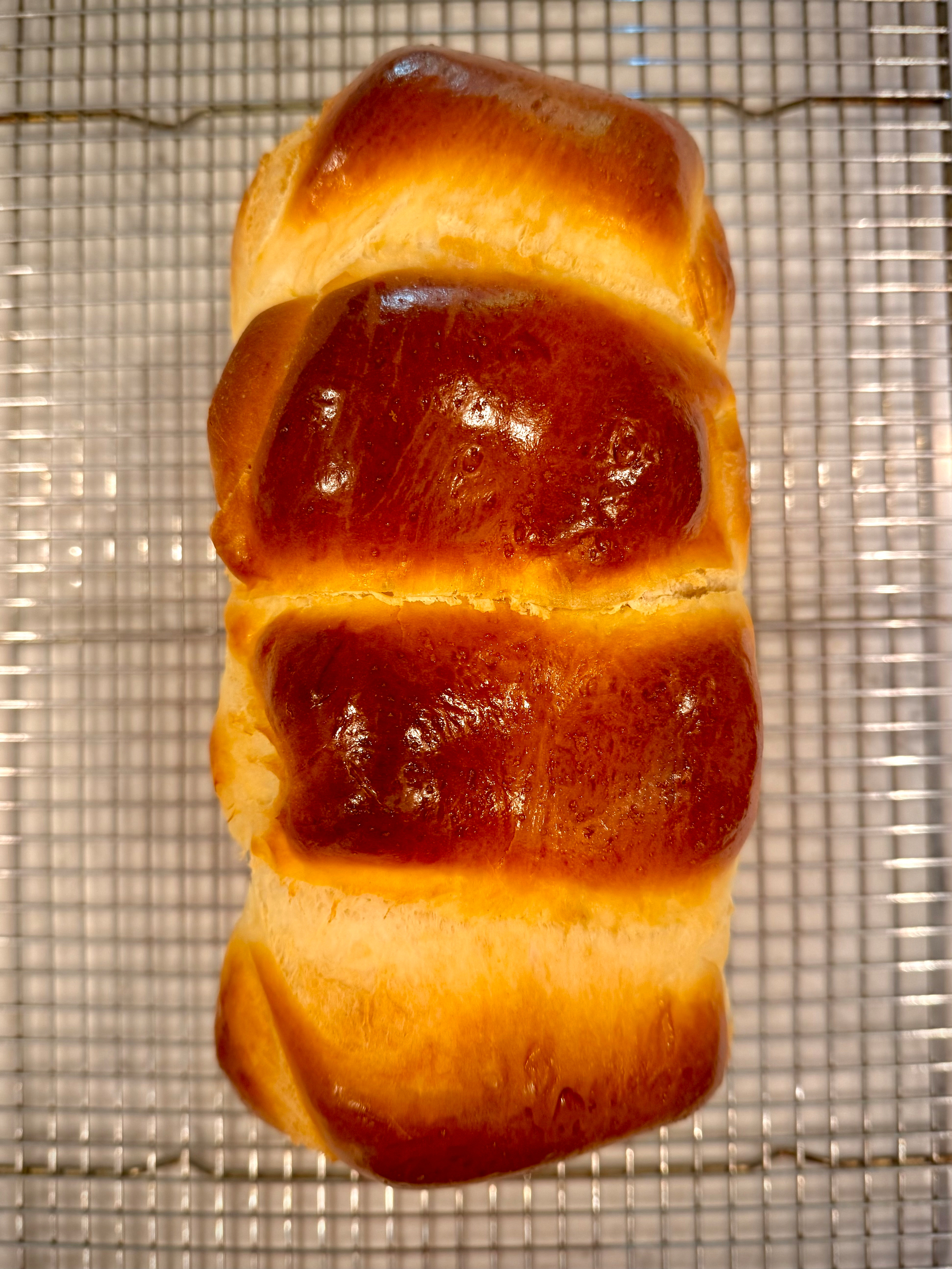 A loaf of fresh baked milk bread on a wire rack