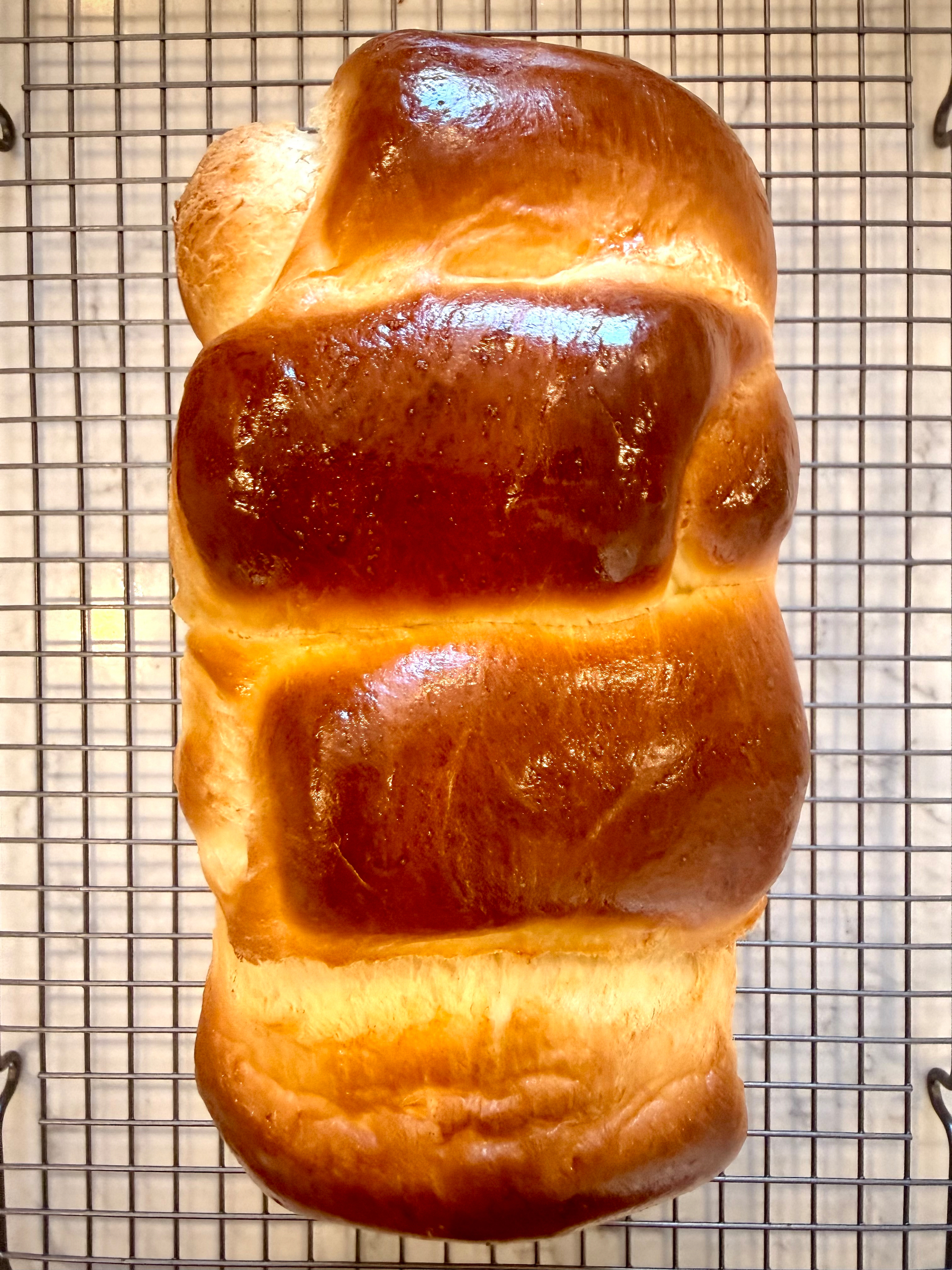 A golden-brown loaf of bread on a cooling rack.