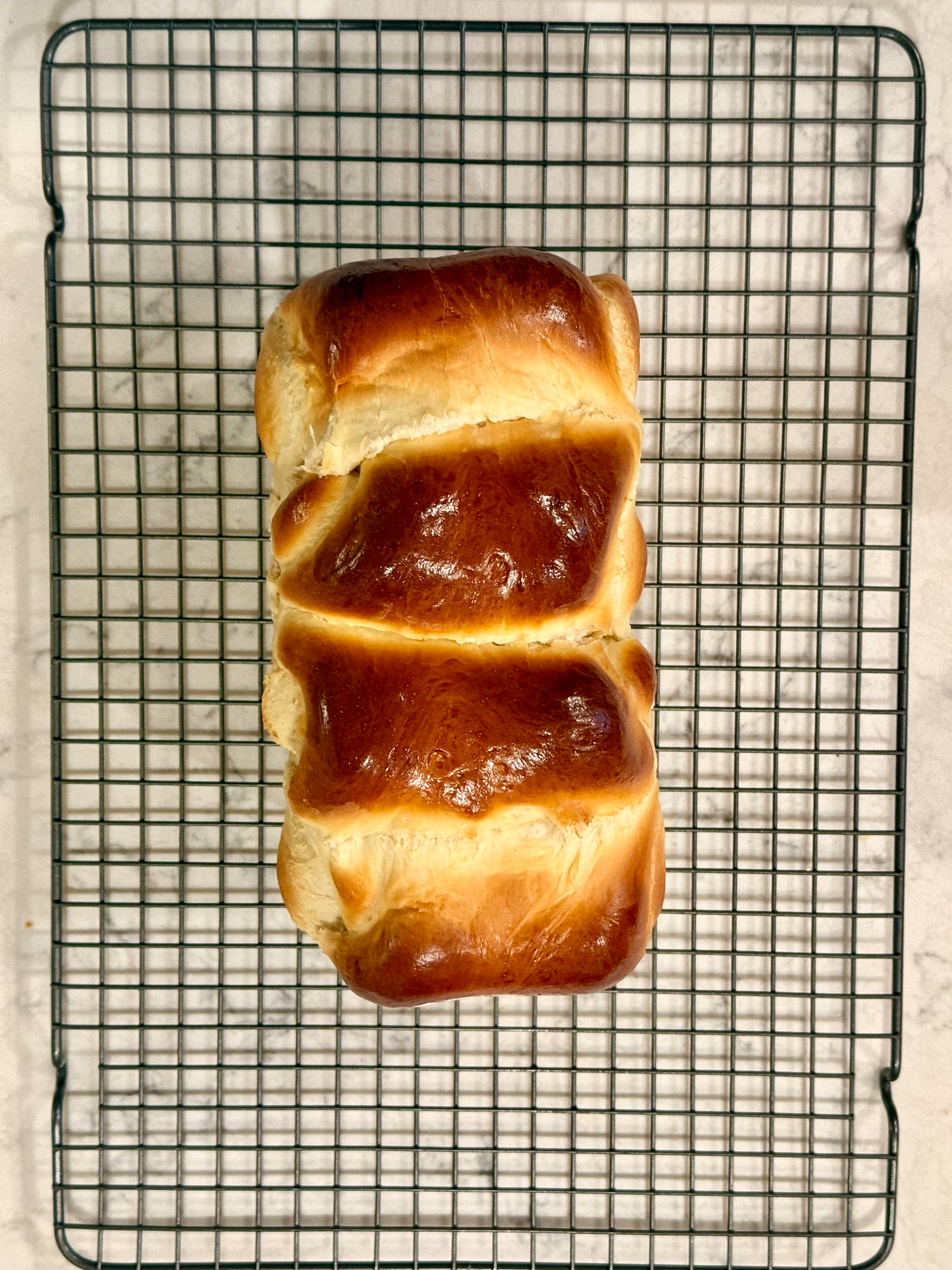 A loaf of freshly baked bread rests on a cooling rack.