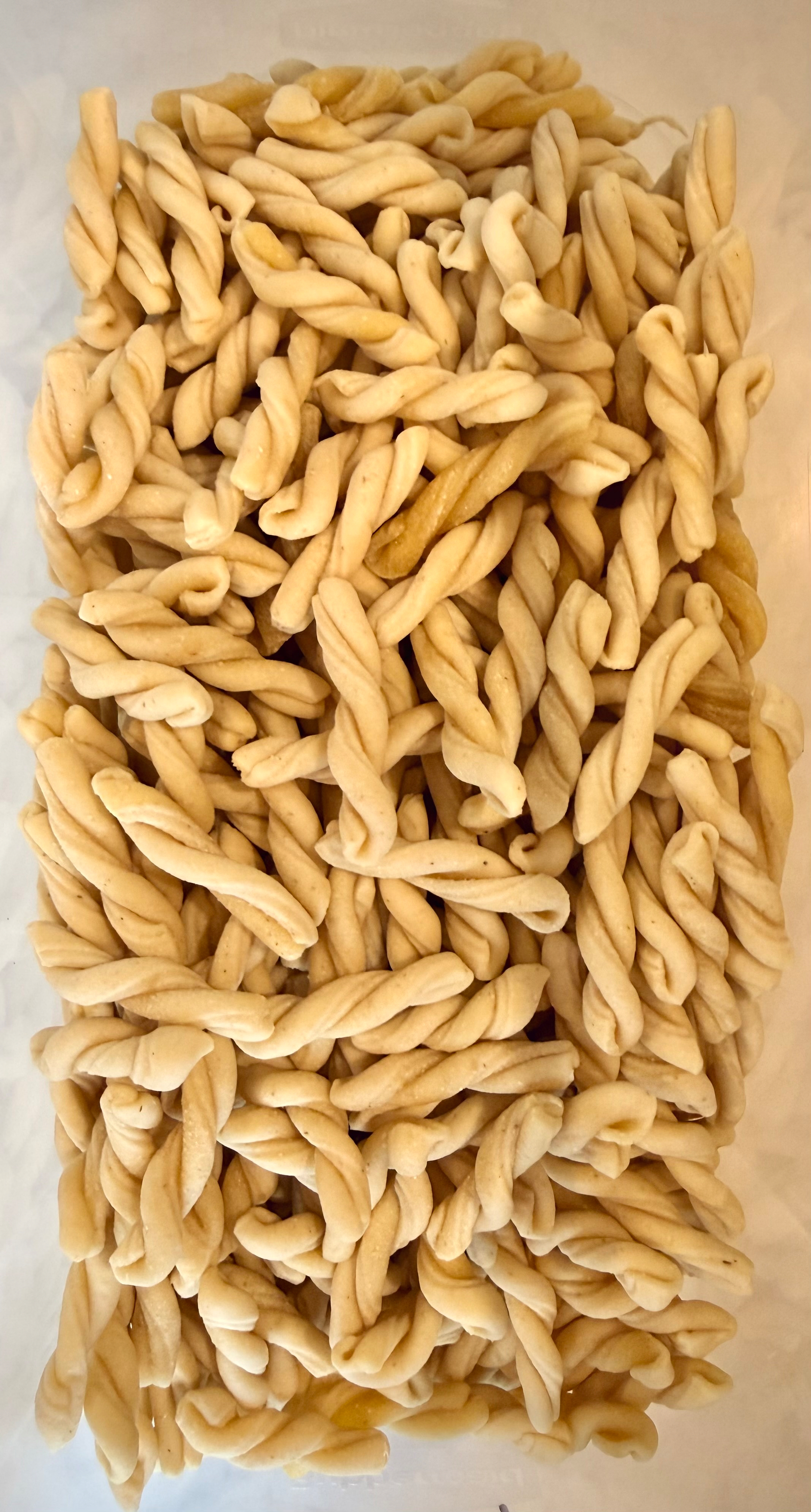 A pile of twisted pasta shapes is arranged on a flat surface.
