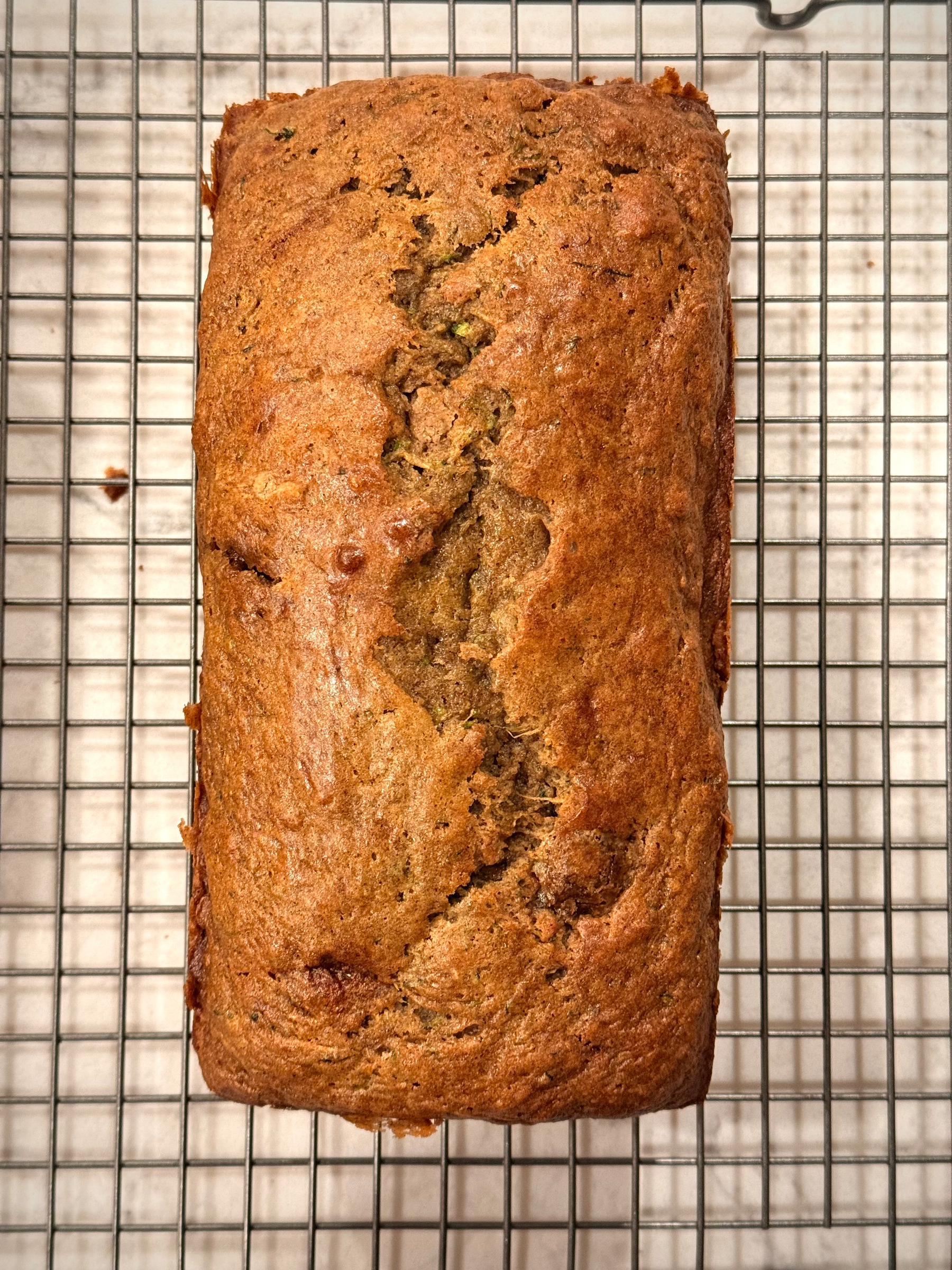 A freshly baked loaf of bread is cooling on a wire rack.