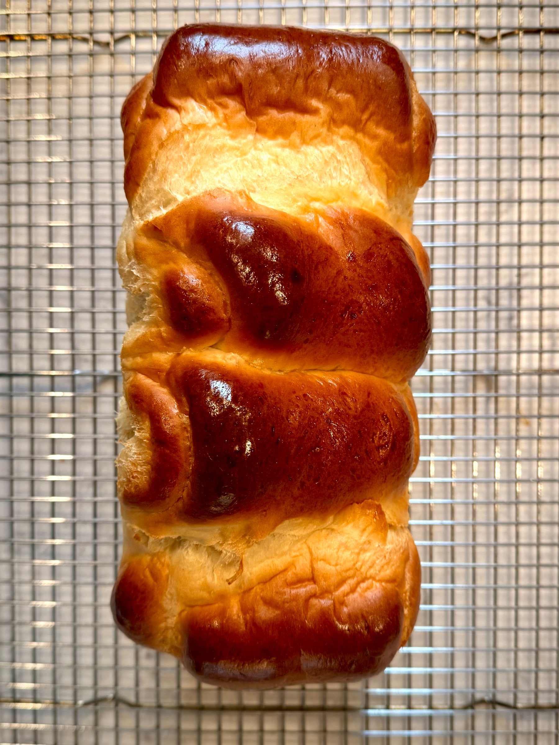 A loaf of golden-brown bread cooling on a wire rack.