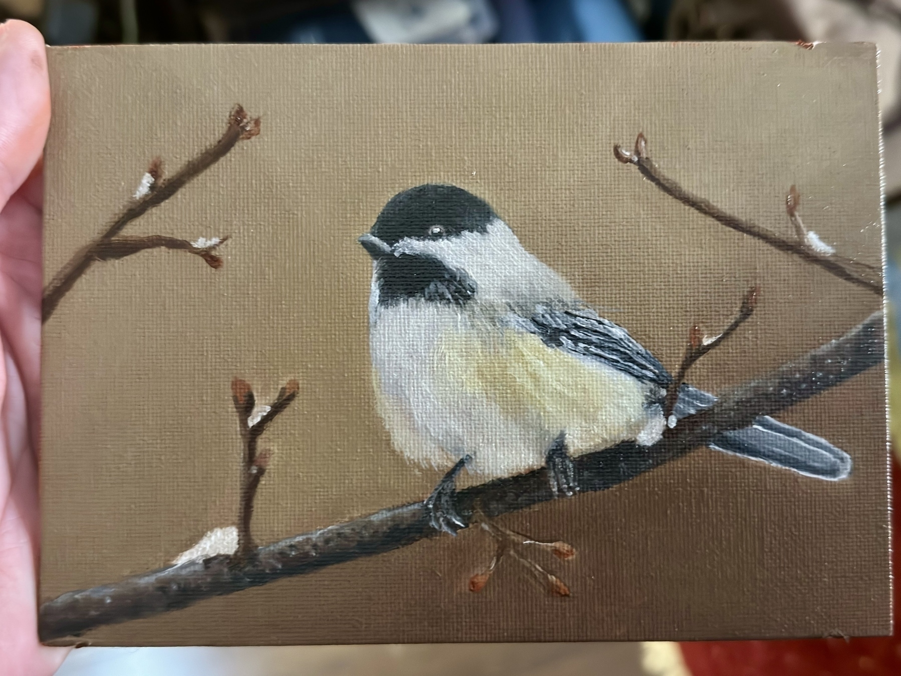 Oil painting of a small chickadee bird with black and white feathers, perched on a bare tree branch against a brown background.