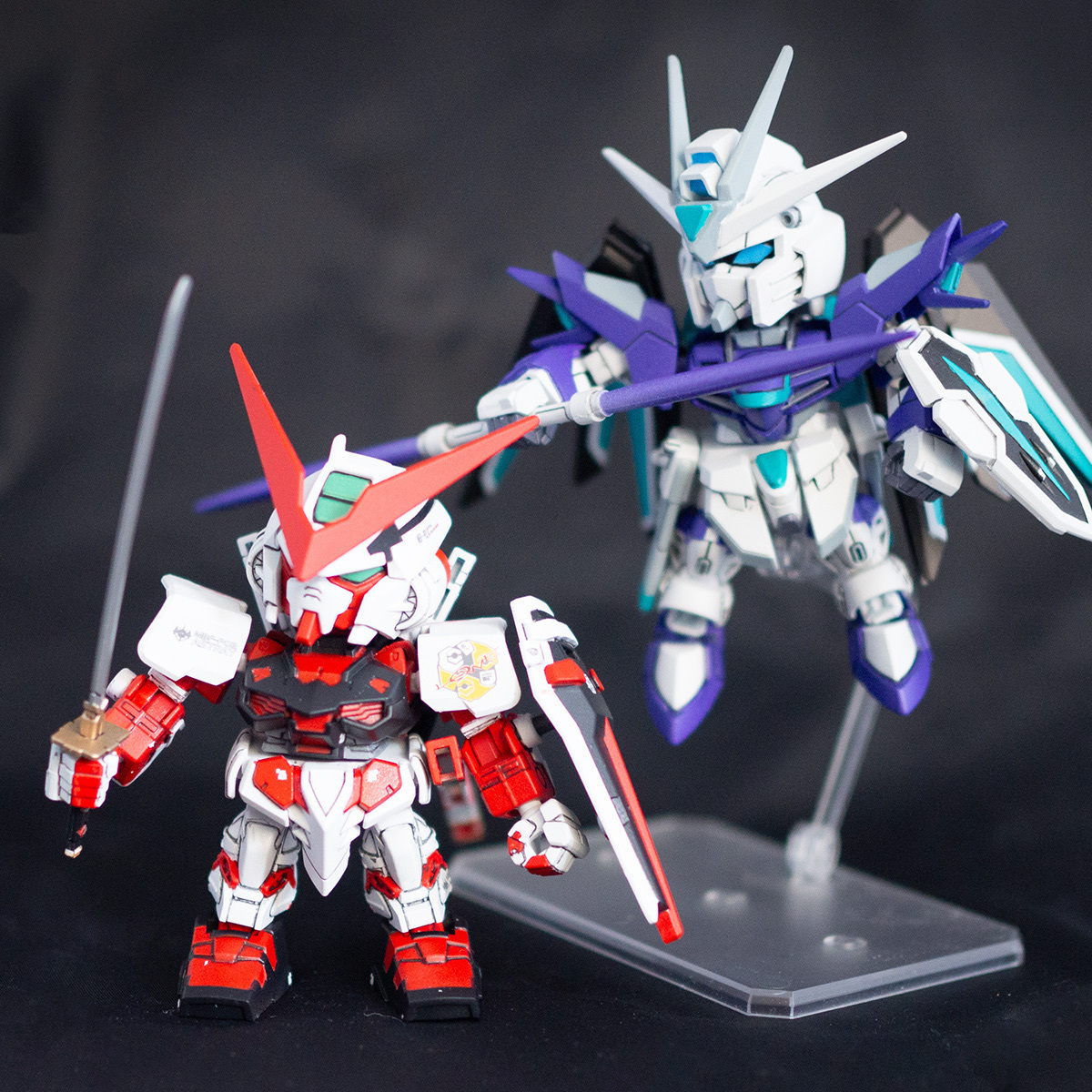 Painted and assembled SD kits. The Astray Red Frame holds a sword in front of an airborne Rising Freedom with custom colors.