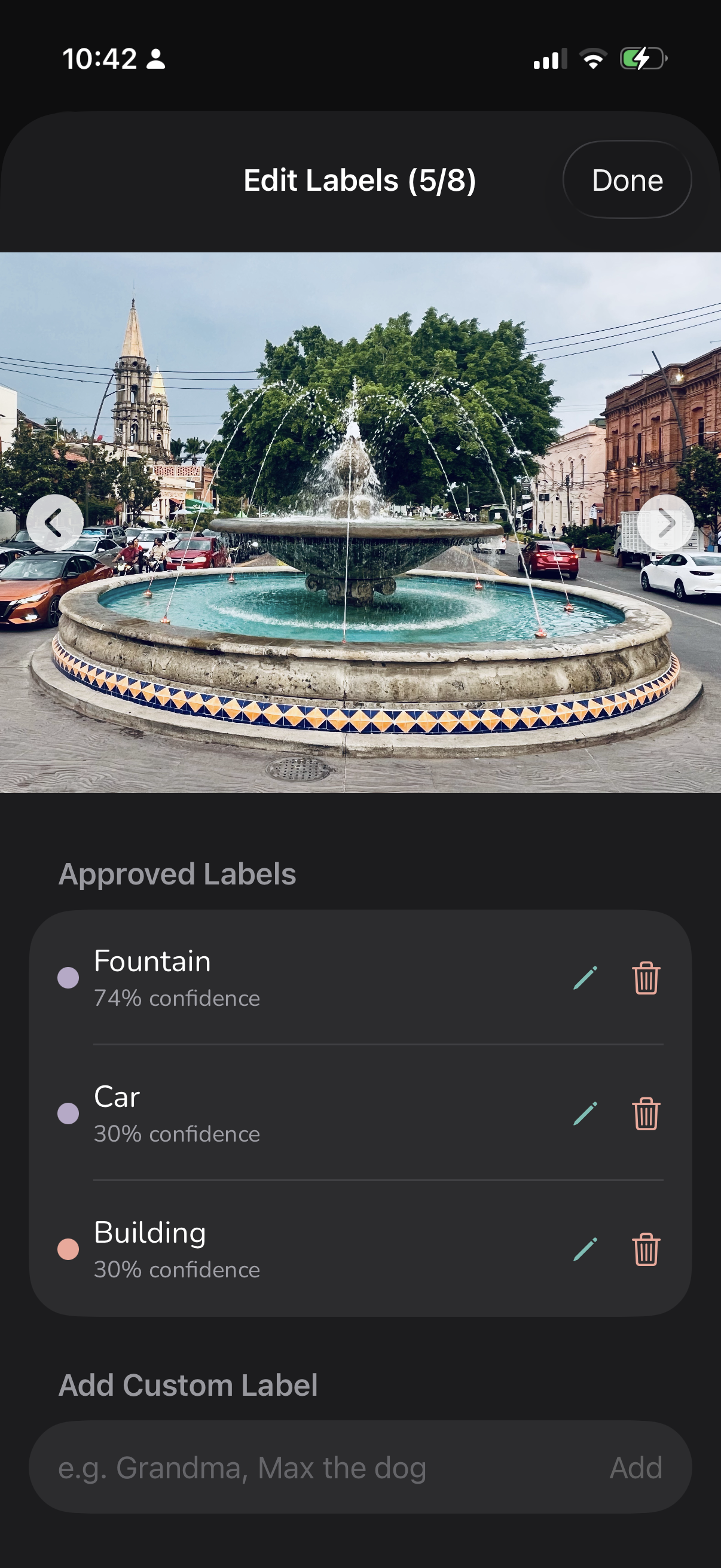 A circular fountain is set in a busy plaza surrounded by cars and historic buildings.