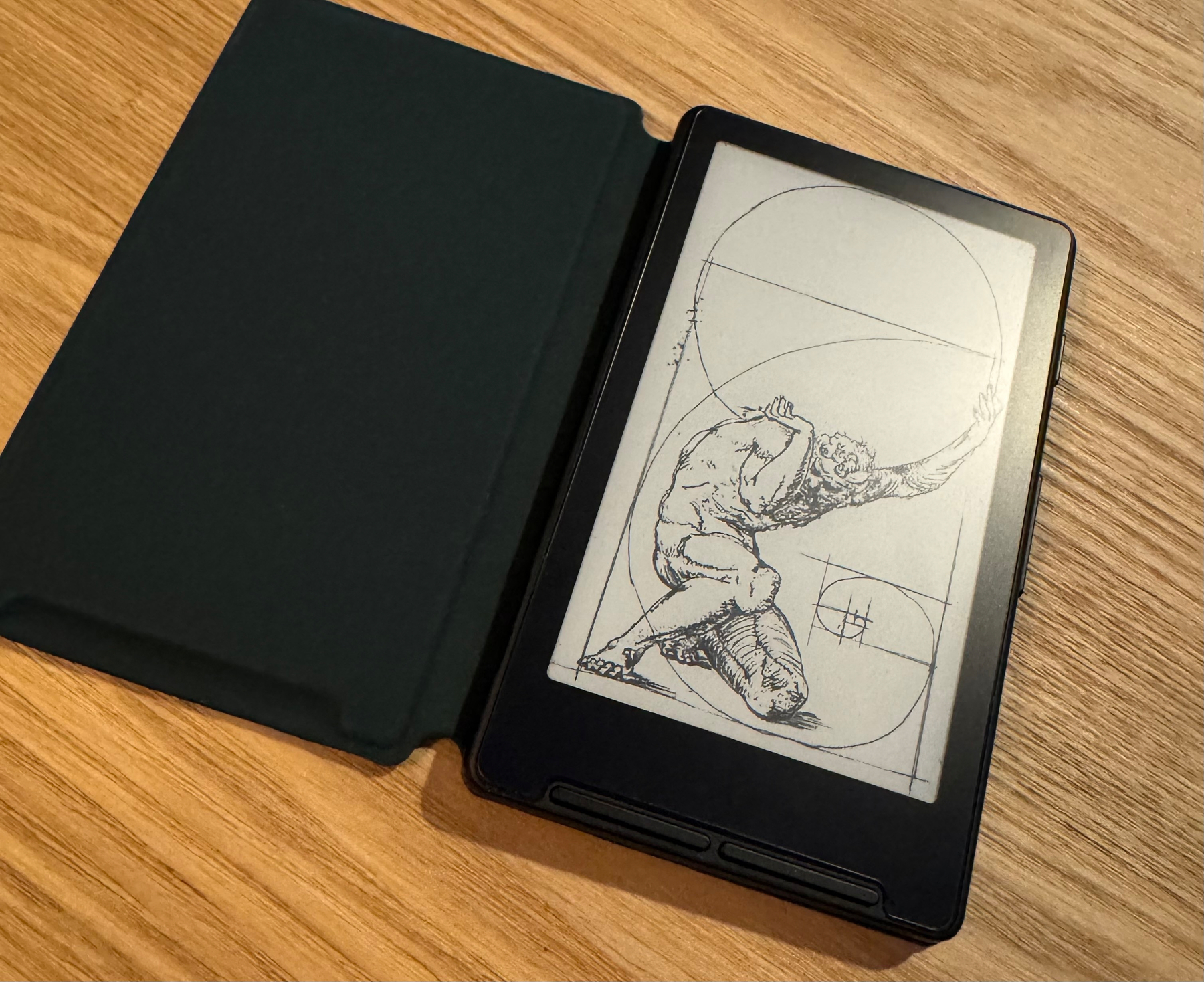 An e-reader displaying a drawing of a person in a dynamic pose with geometric shapes is shown next to an open cover on a wooden surface.