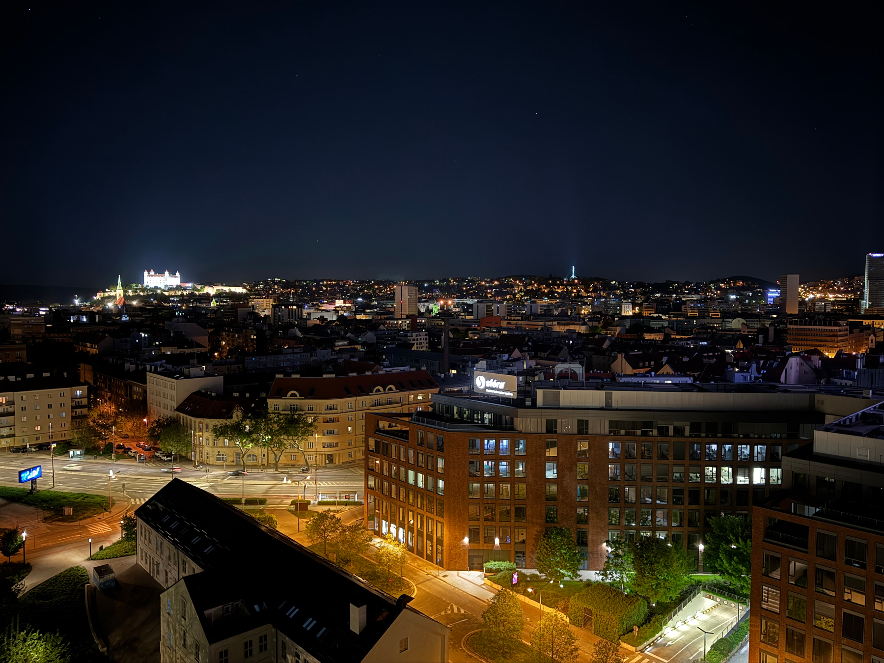 A nighttime cityscape with illuminated buildings and streets stretches beneath a dark sky.