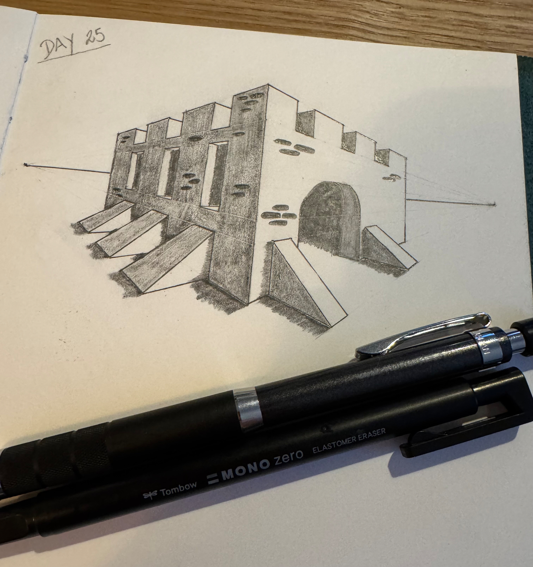 A 3D drawing of a castle sits on graph paper alongside two pens, labeled Day 25.