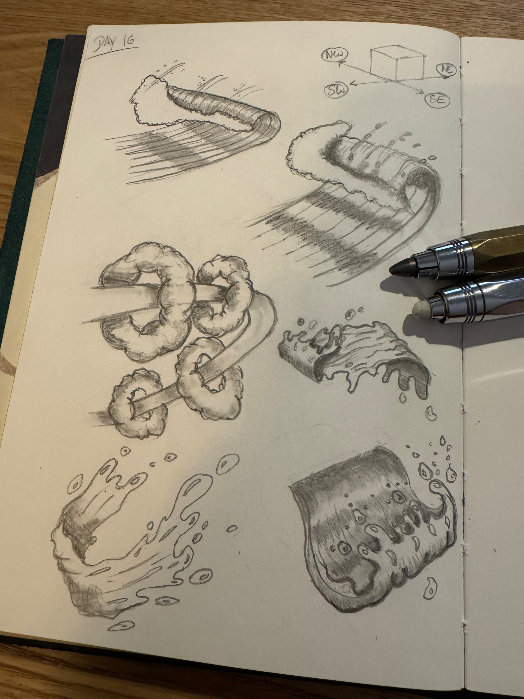 Various sketches of abstract forms and ribbon-like objects in motion are drawn in pencil on a sketchbook page with two pens placed on the side.