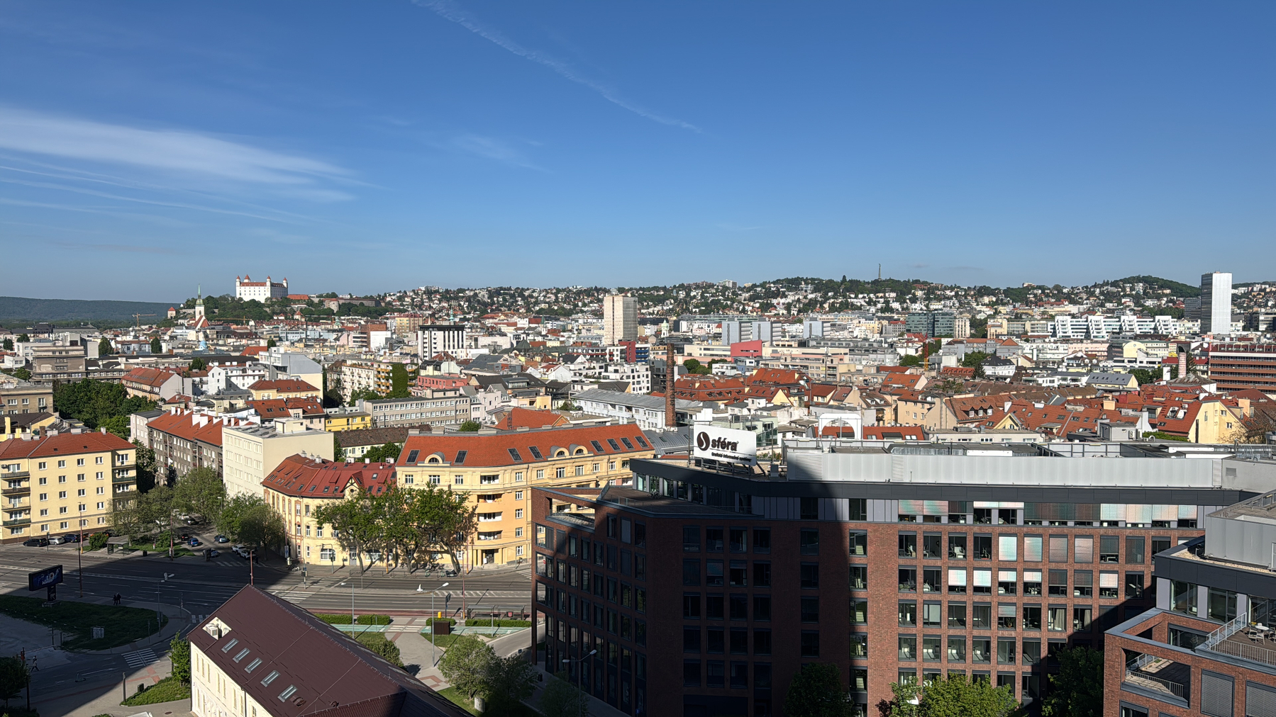 A panoramic view of a cityscape with a mix of modern and traditional architecture under a clear blue sky.