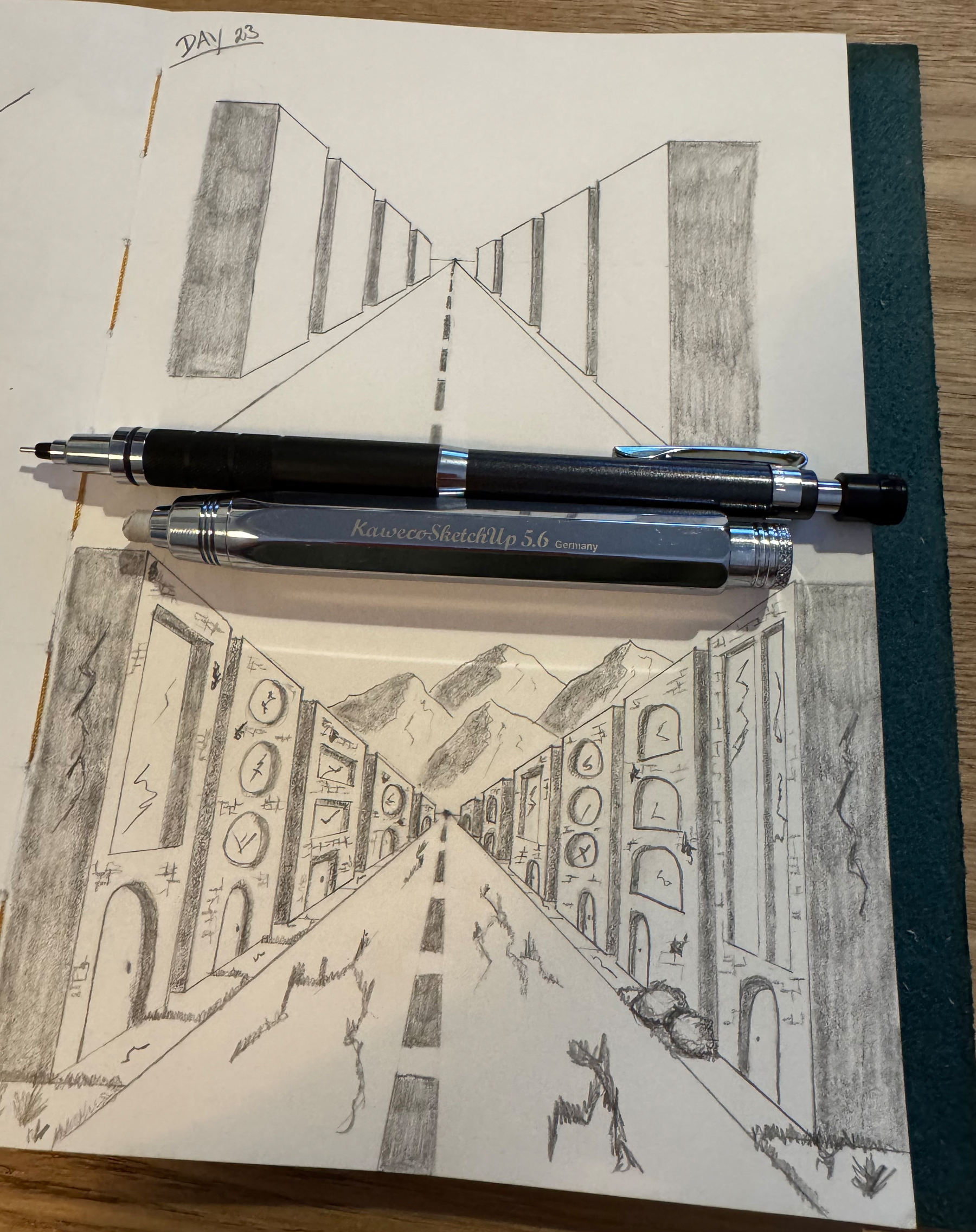 Two pencil drawings depict roads with geometric structures, accompanied by mechanical pencils resting on the paper.