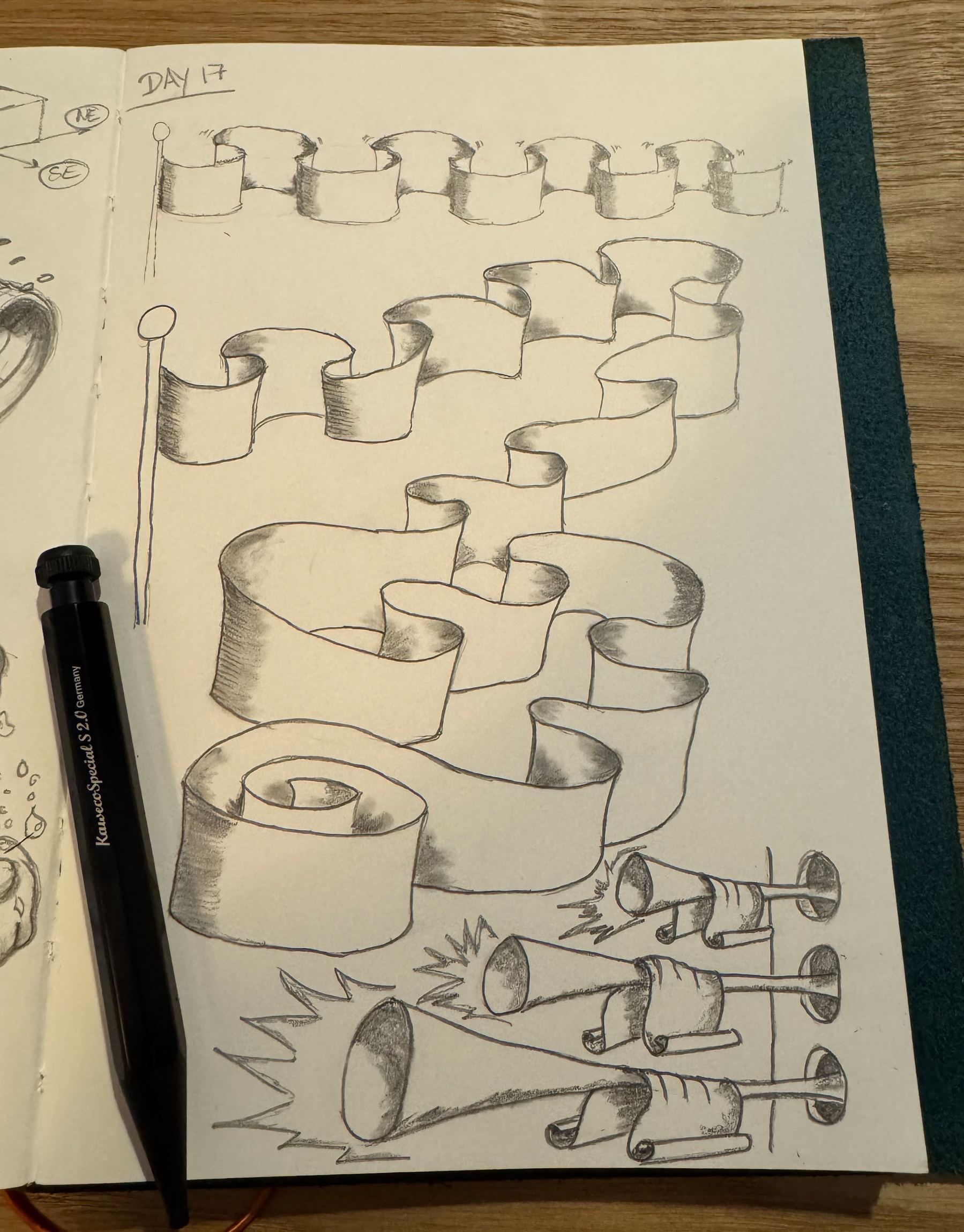 A sketchbook page displays a series of pencil drawings of ribbons in various forms, accompanied by a black pen placed on top.