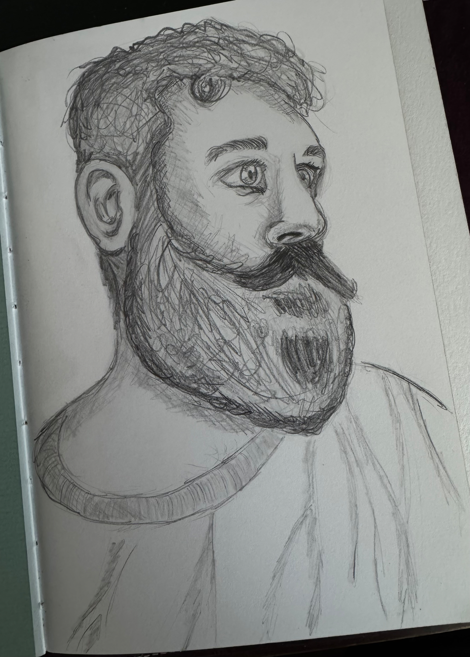 A sketch of a bearded person in profile view is drawn on a piece of paper.